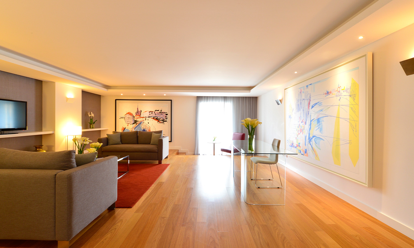 La Suite Presidencial del Pestana Cidadela Cascais tiene una sala con un escritorio transparente y silla, cuadros y un sofá