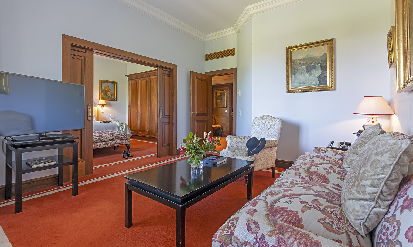 La Suite del Pestana Palace Lisboa tiene una sala de estar con un sofá y un sillón, una mesa de centro y una televisión
