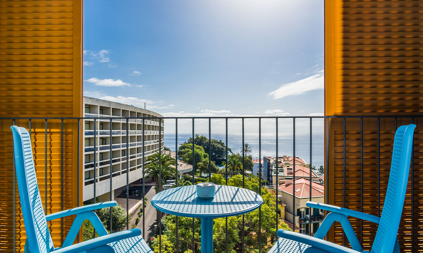 El Estudio Deluxe Vista Mar del Pestana Casino Studios tiene una terraza con vista a la ciudad y una mesa con sillas azules