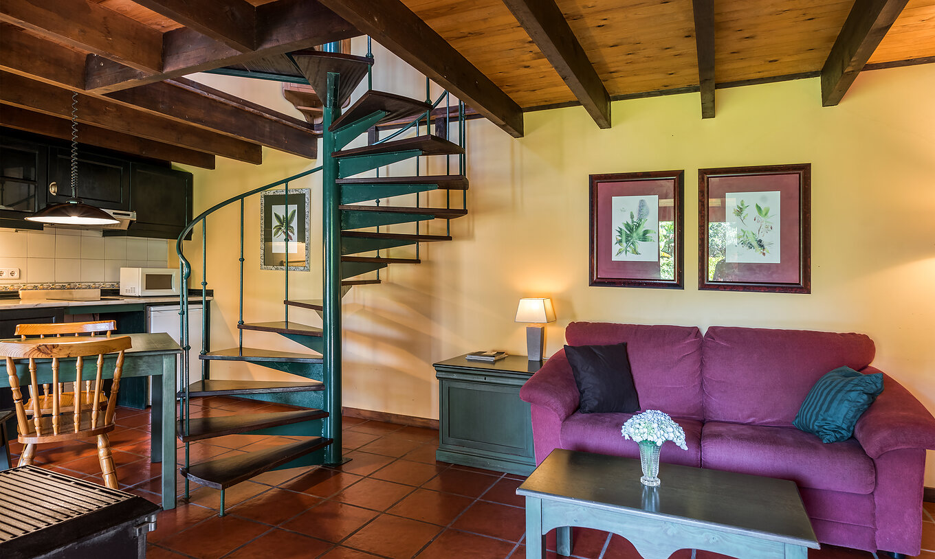 Las Villas Duplex del Pestana Quinta do Arco tienen un sofá con mesa de apoyo, cocina, mesa de comedor y escaleras metálicas