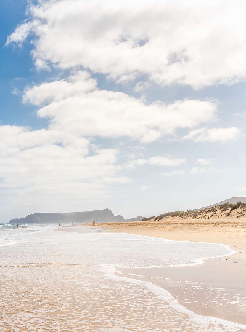 Playa extensa en Porto Santo con arena clara, olas calmadas y un cielo azul con algunas nubes