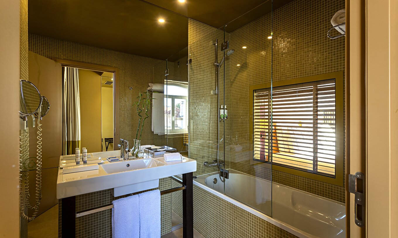 El Deluxe Grand View tiene un baño con bañera y una ventana al dormitorio