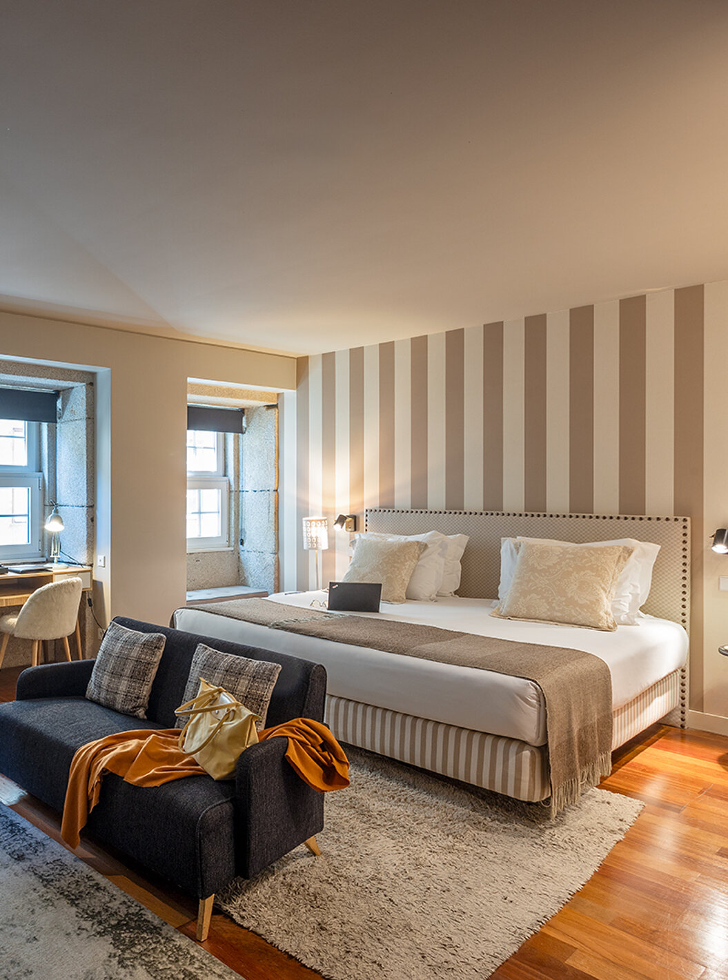 La Heritage Suite del Pestana Vintage Porto tiene una cama doble, dos sofás sobre alfombras y varias ventanas