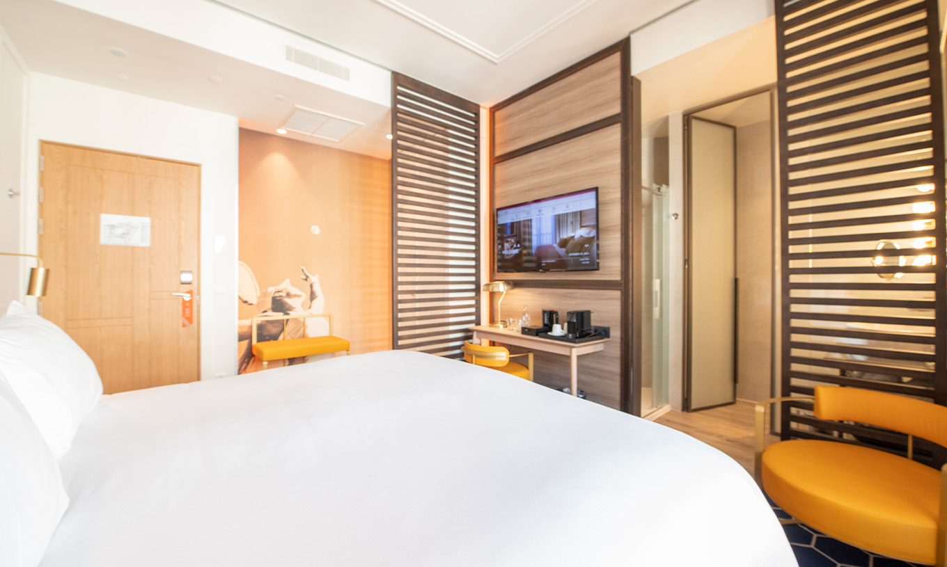 El The Legend Room del Pestana CR7 Gran Vía Madrid tiene cama doble, silla y lámpara, dos bancos y divisoria de madera