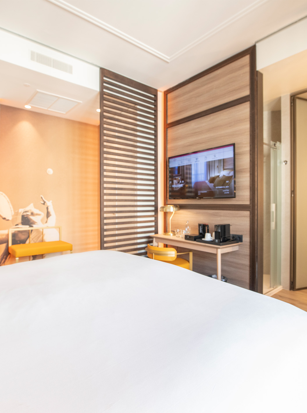 El The Legend Room del Pestana CR7 Gran Vía Madrid tiene cama doble, silla y lámpara, dos bancos y divisoria de madera