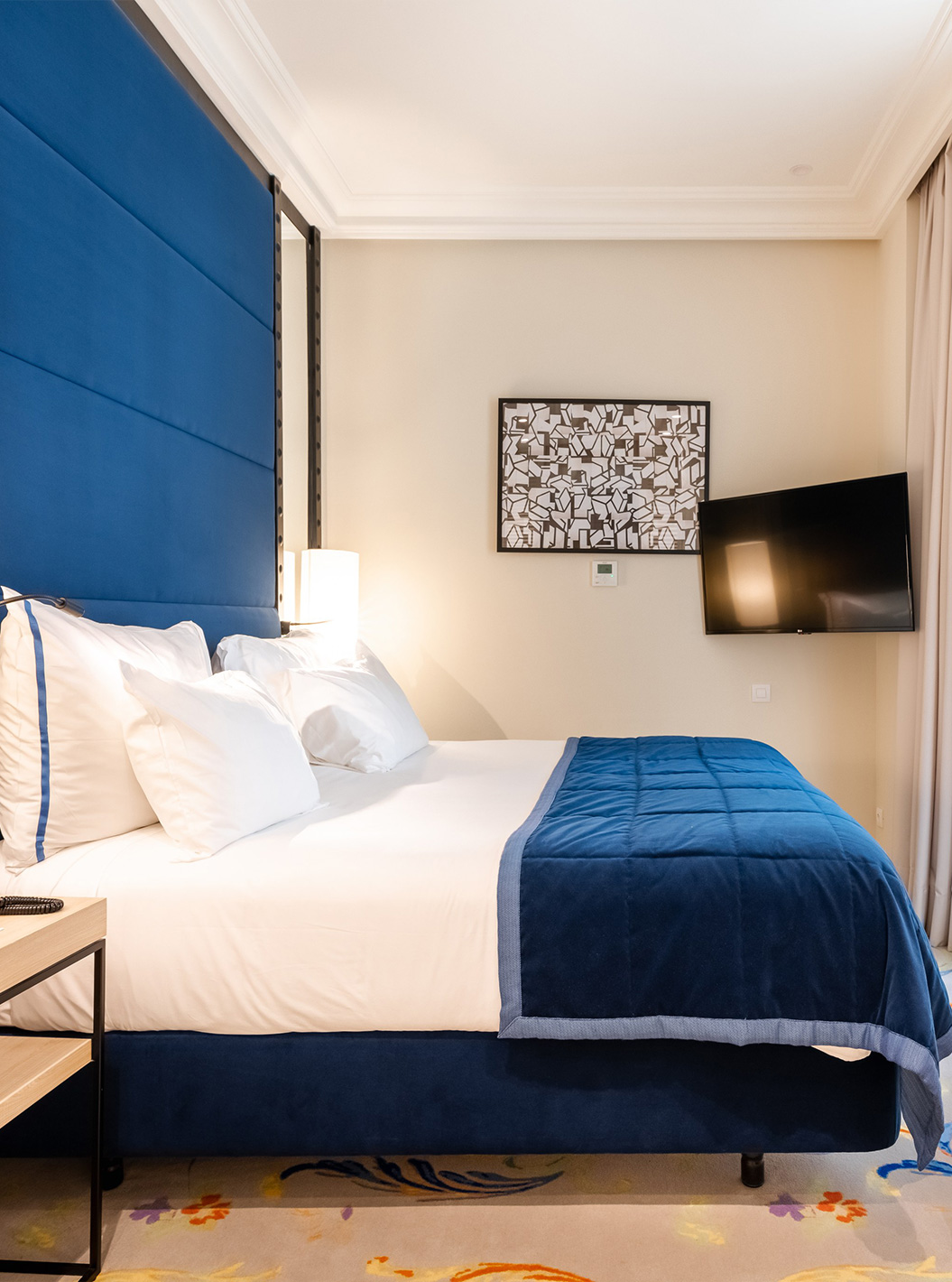 La habitación Superior del Pestana Plaza Mayor Madrid tiene una cama doble, un cabecero azul, una televisión y espejos