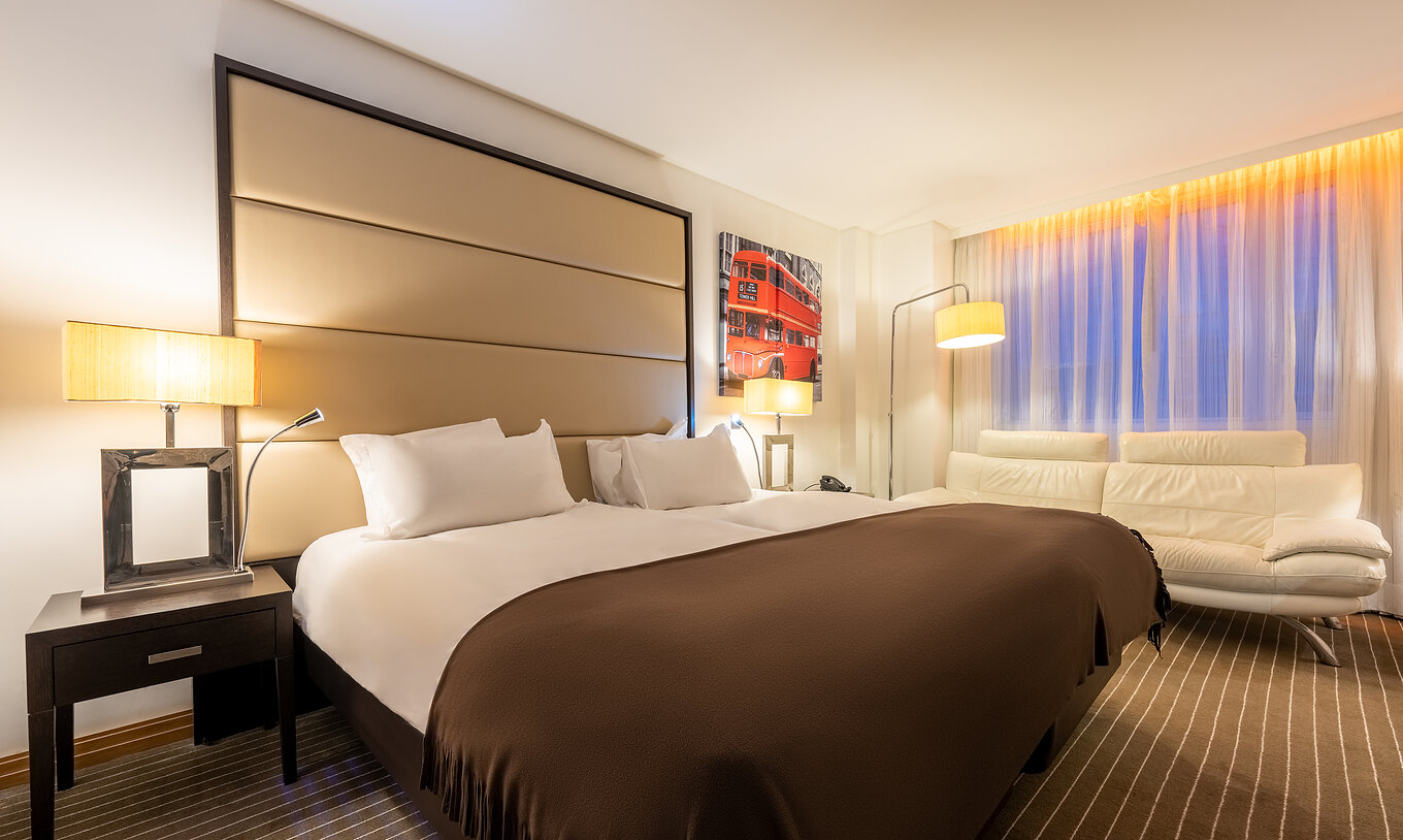 El Premium Twin del Pestana Chelsea Bridge tiene dos camas juntas, mesa de noche, sofá, lámparas y ventanas con cortinas