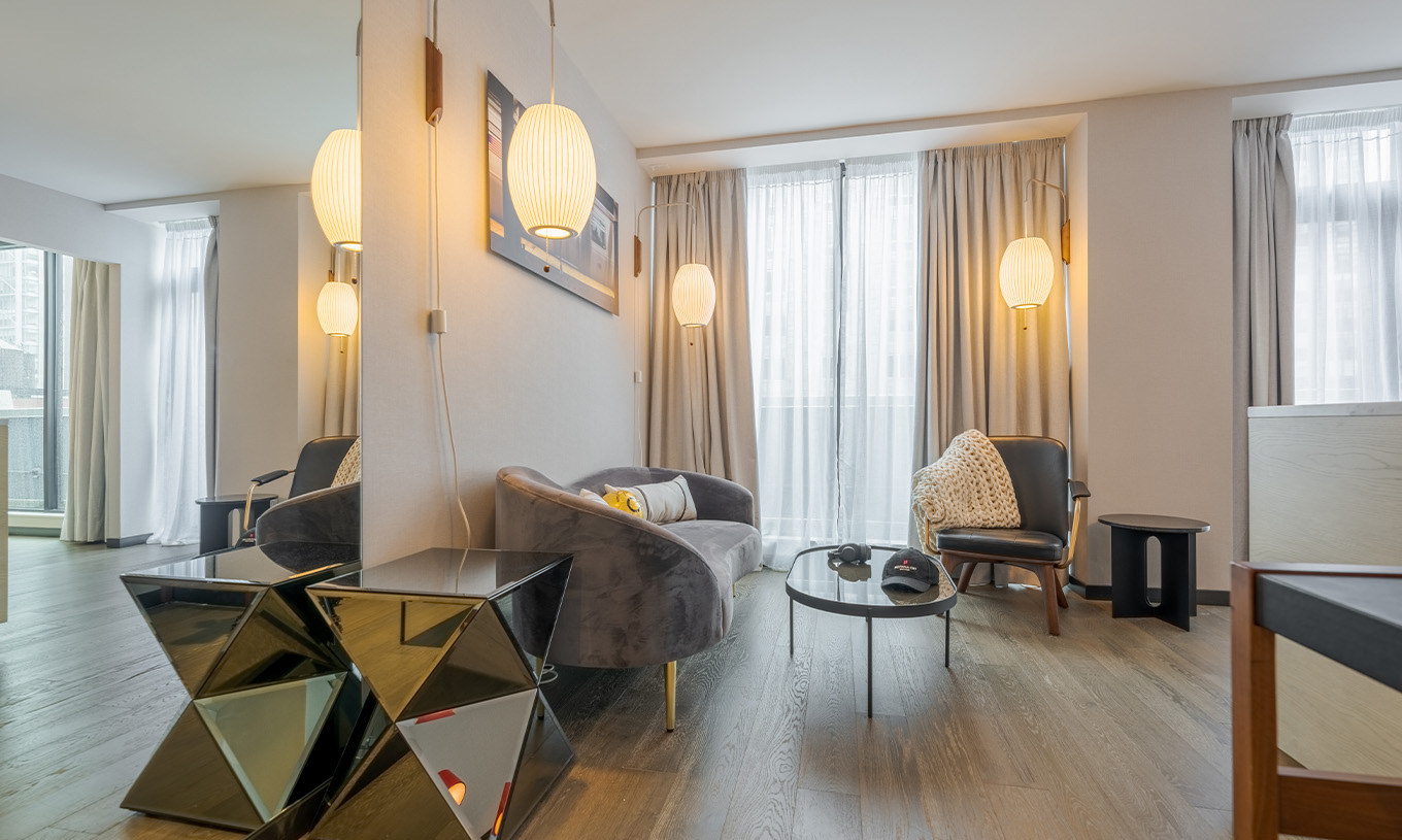 La Suite Junior con Balcón y Vista del Pestana CR7 Times Square tiene una sala de estar con sofá, ventanas grandes y silla