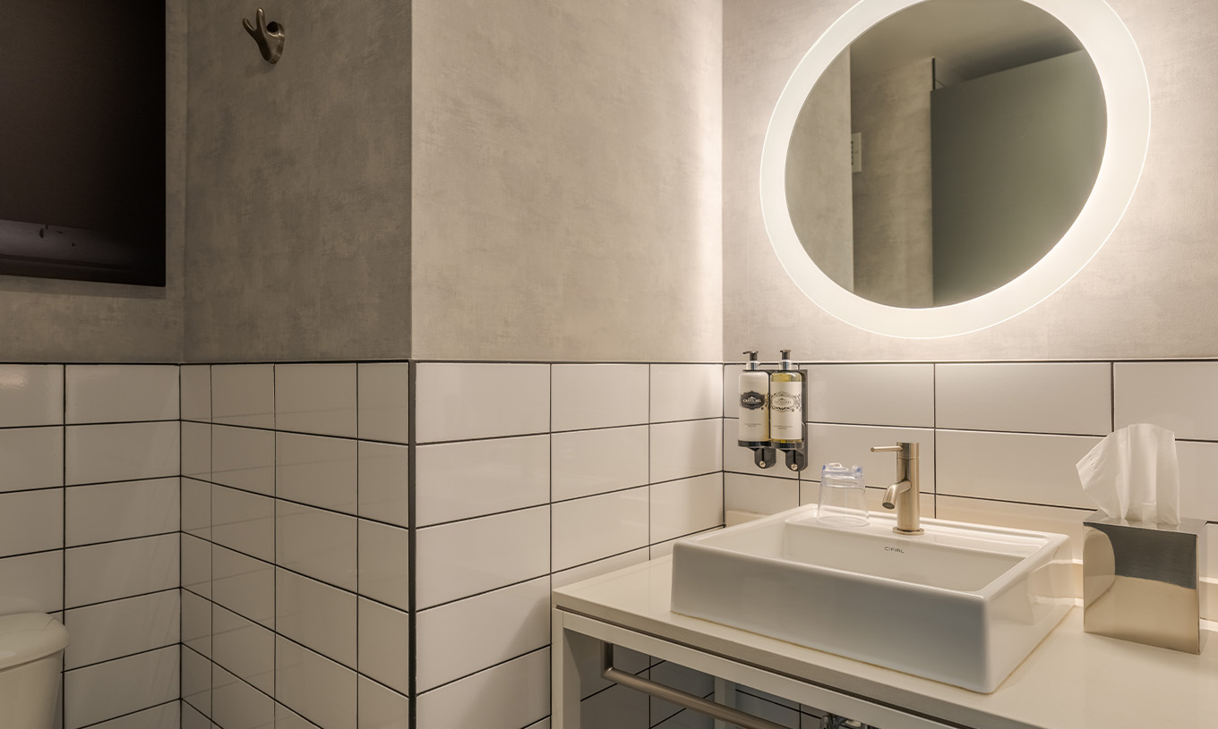 El Superior Double del Pestana CR7 Times Square tiene un baño con lavabo y un espejo redondo con luz alrededor