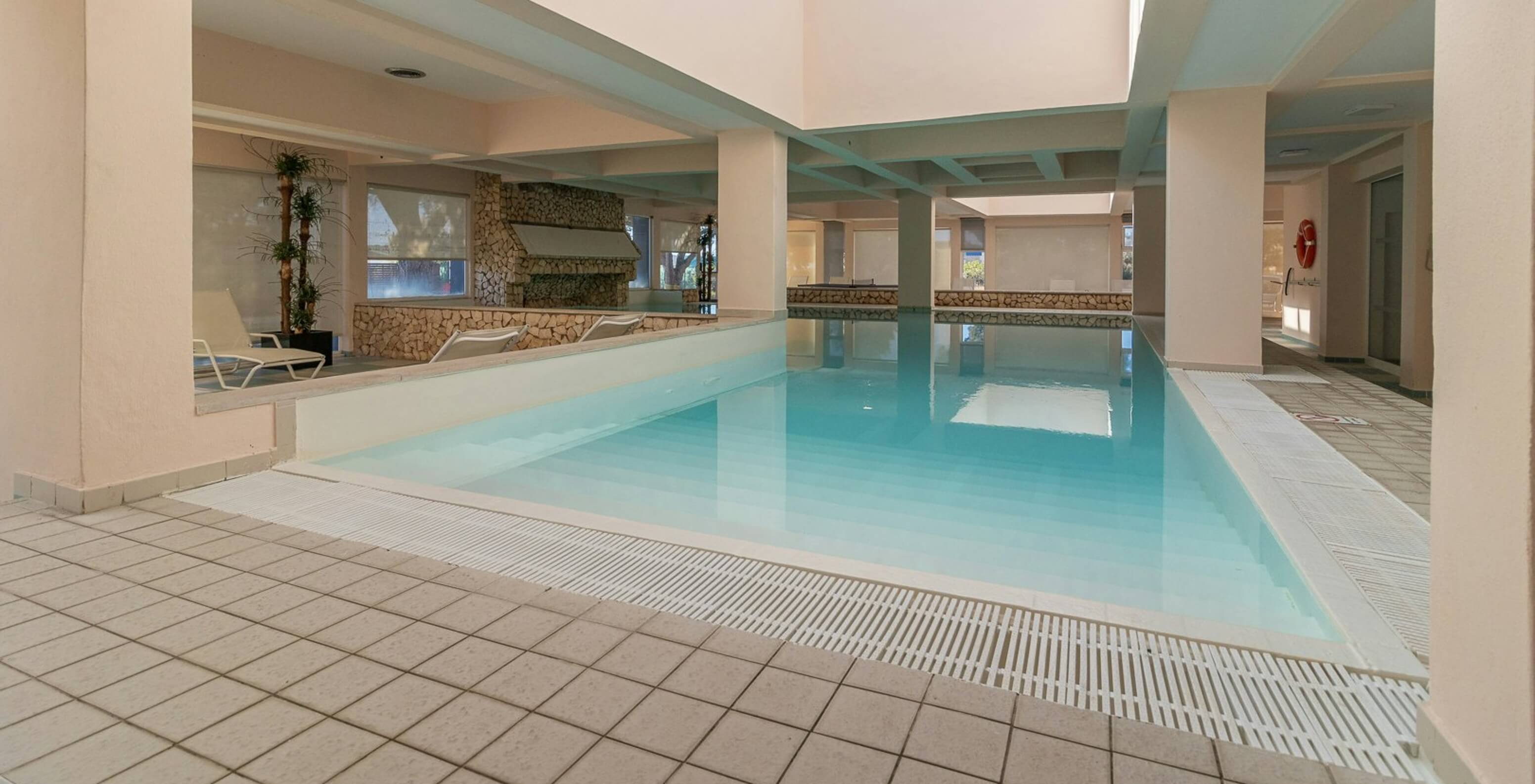 Piscina interior con luz natural y tumbonas en el apartahotel frente al mar