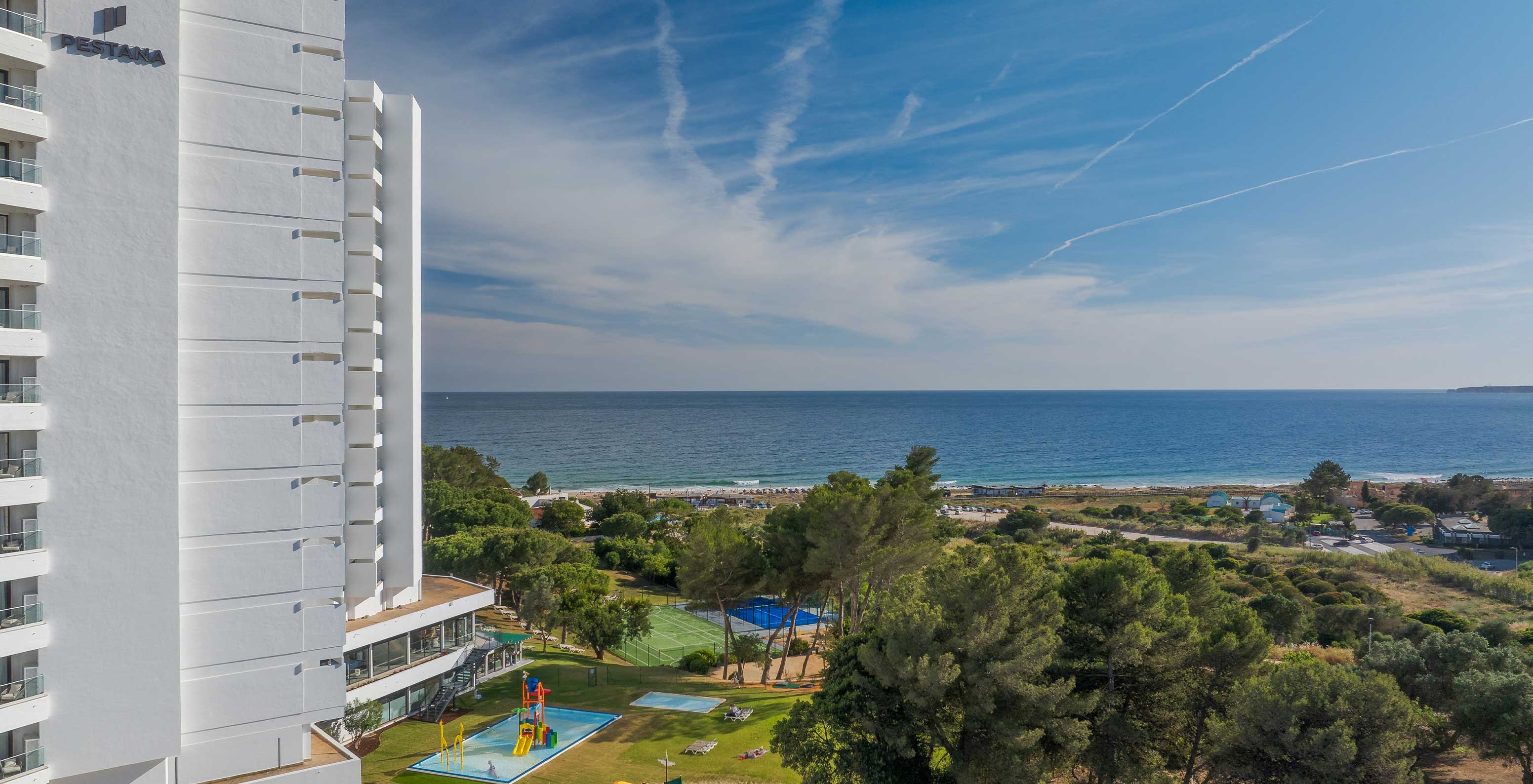Vista exterior del hotel Pestana Blue Alvor Beach, donde se ve la vegetación verde y el mar azul al fondo