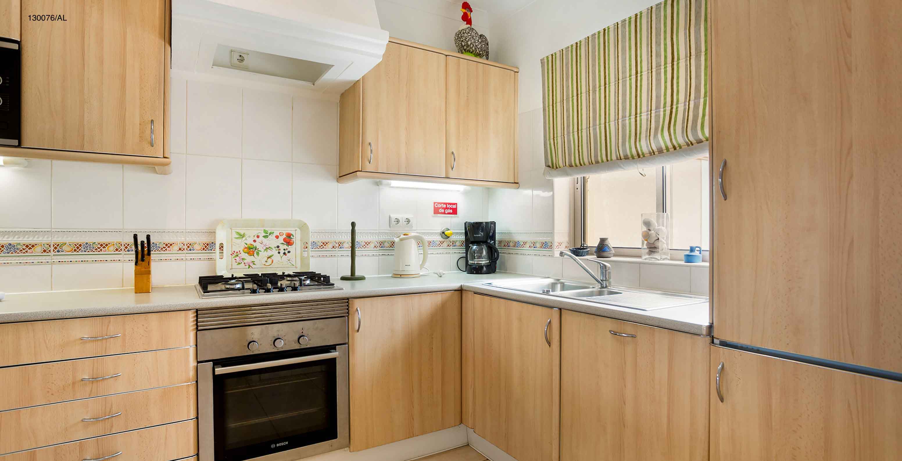 El apartamento Pestana Carvoeiro Golf T2 Estándar tiene una cocina equipada con gabinetes de madera y electrodomésticos