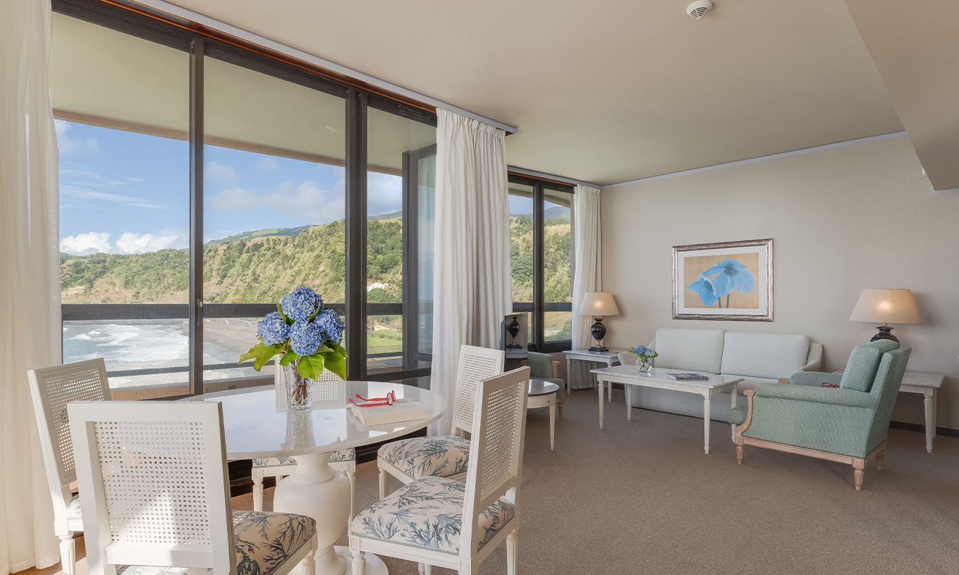 La Suite del Pestana Bahia Praia tiene sala con vista a la playa junto al hotel y a la naturaleza verde