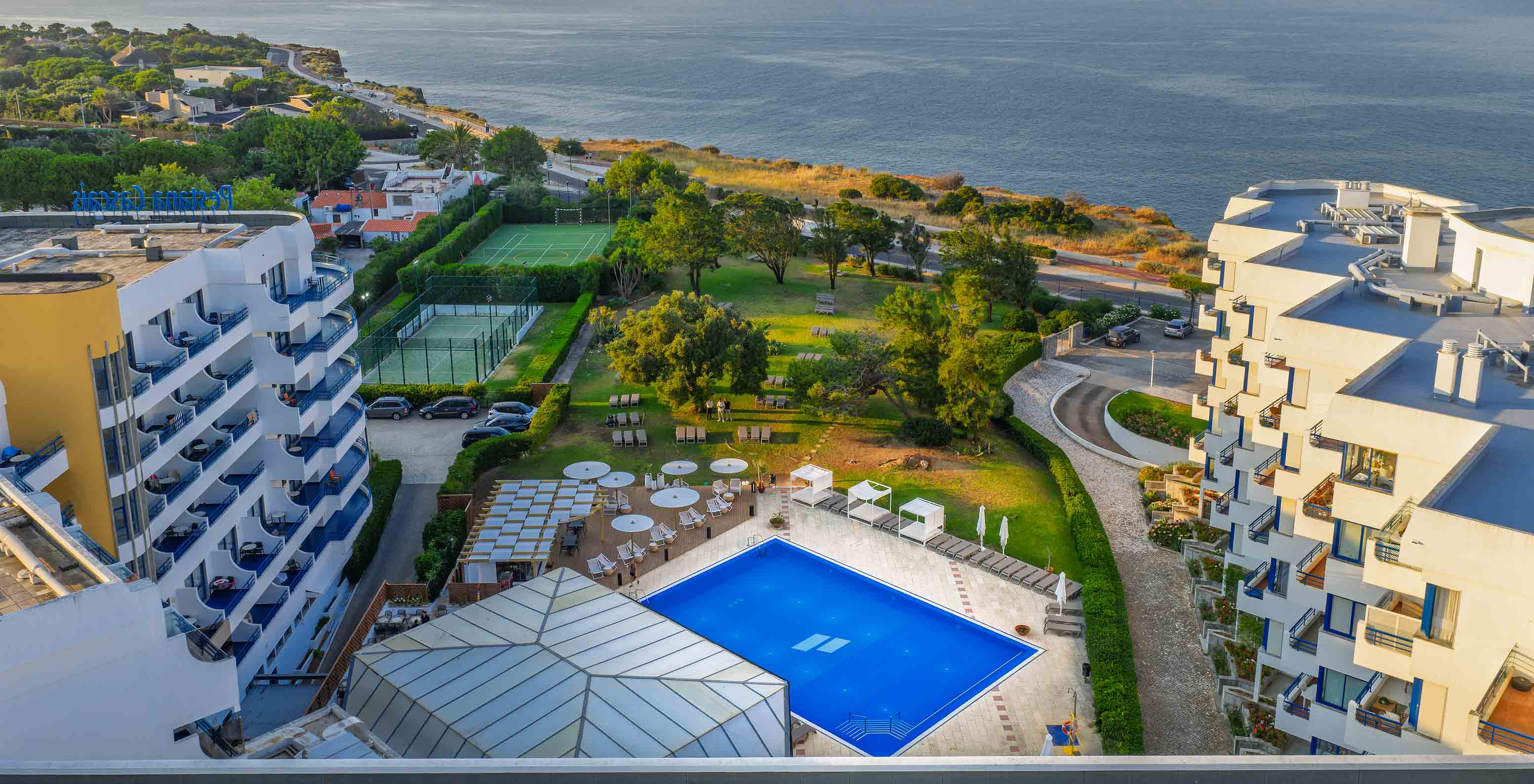 Vista aérea del hotel con la piscina exterior, los jardines y vista al mar