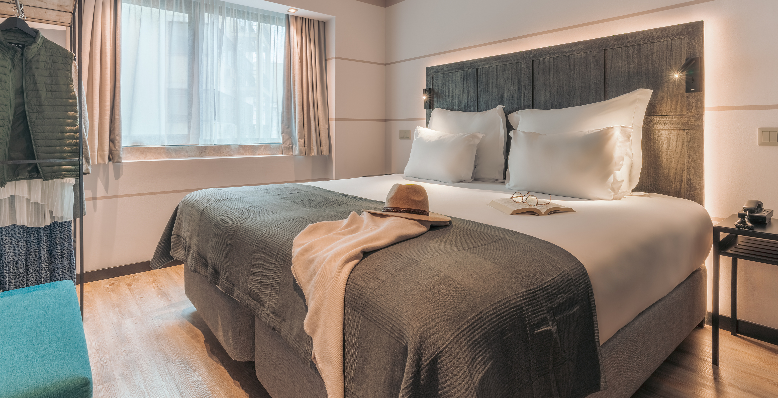 La Junior Suite del Pestana Lisboa Vintage tiene una cama matrimonial con una manta, un sofá azul, mesa de noche y un armario