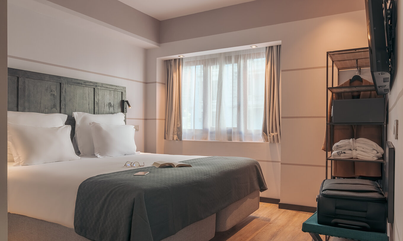 El Double Deluxe Studio del Pestana Lisboa Vintage tiene una cama matrimonial con una manta gris y un armario con un abrigo