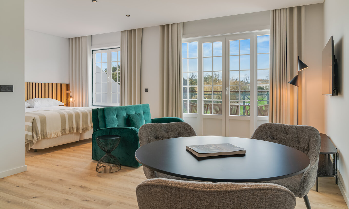 El Familiar con Terraza - Clubhouse del Pestana Sintra Golf tiene una mesa para comidas y dos ventanas con terraza