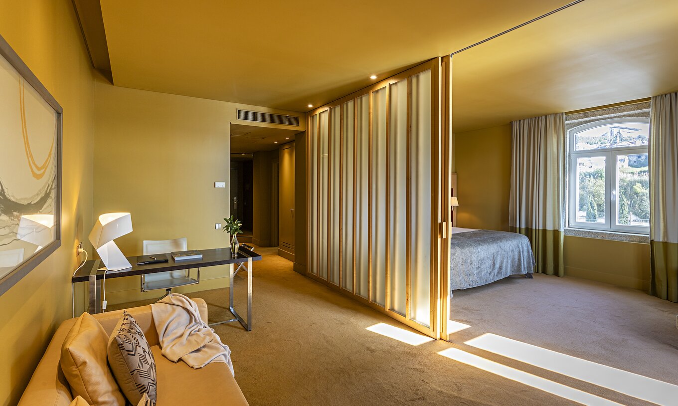 La Standard Suite tiene una cama doble con una separación hacia la sala con sofá y escritorio