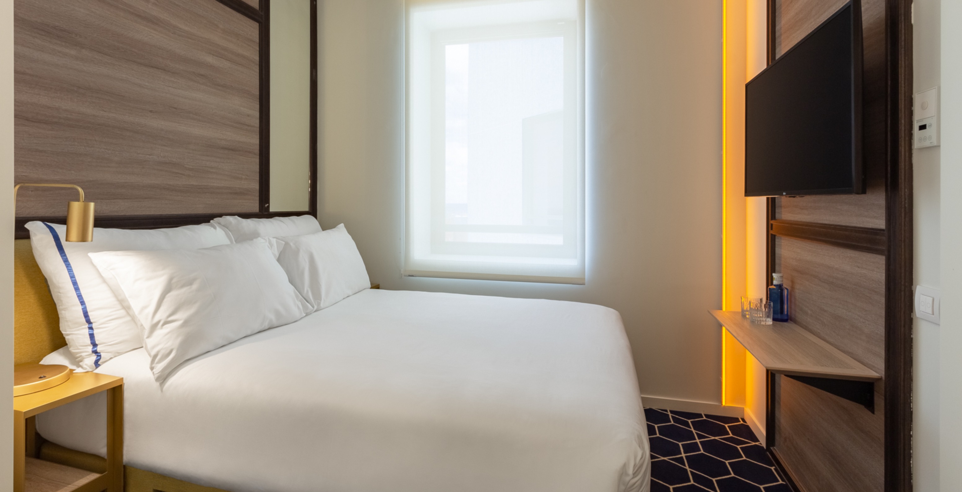 La Habitación Doble Pequeña del Pestana CR7 Gran Vía Madrid tiene una cama doble, una ventana y una mesita de noche amarilla