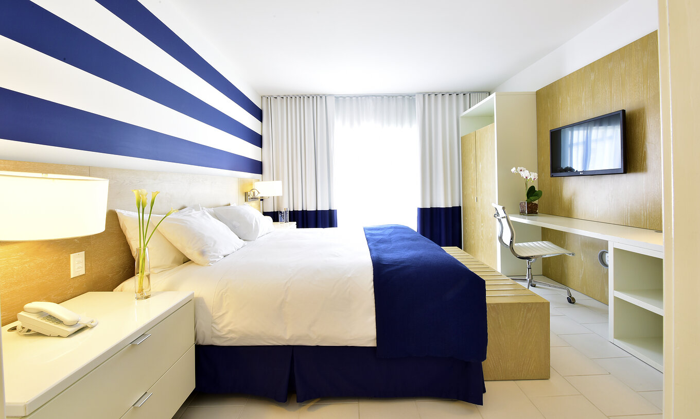 La Suite King con Balcón del Pestana Miami es moderna con cama grande y decoración azul y blanca.
