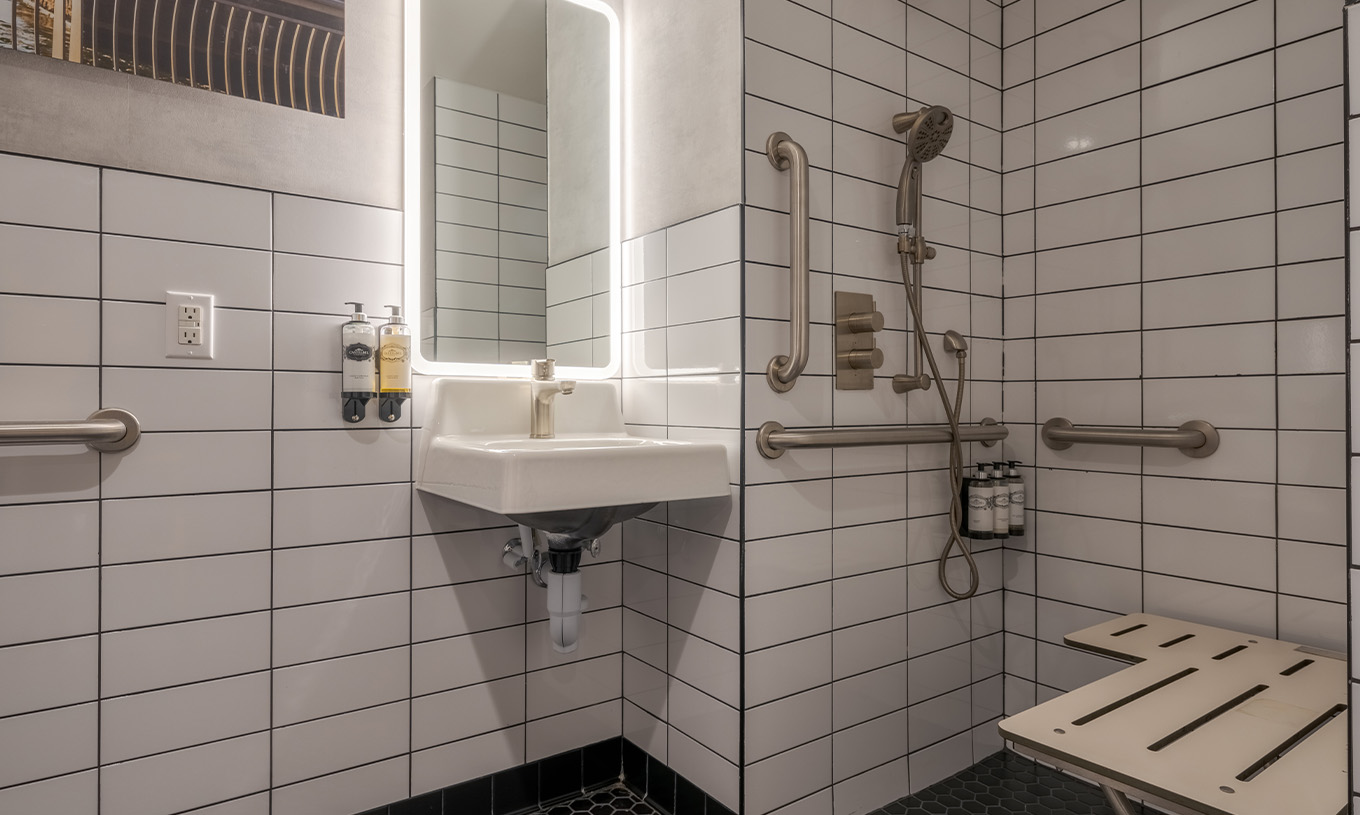 El Comfort Double ADA del Pestana CR7 Times Square tiene un baño adaptado con ducha, lavabo y espejo