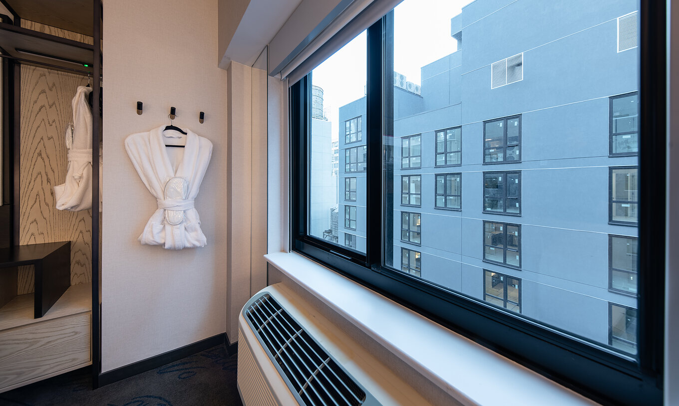 El Superior King High Floor del Pestana CR7 Times Square tiene una bata y una ventana con vista a otro edificio