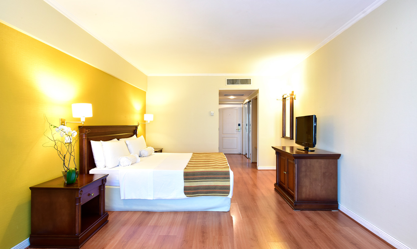 La Chambre Queen Deluxe du Pestana Buenos Aires a un Lit Double, Télévision, Miroir et Table de Chevet avec Lampe
