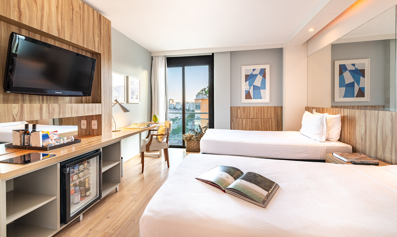 Le Chambre Vue Mer Latérale du Pestana Rio Atlântica a deux lits, télévision, et fenêtre avec vue sur la plage de Copacabana