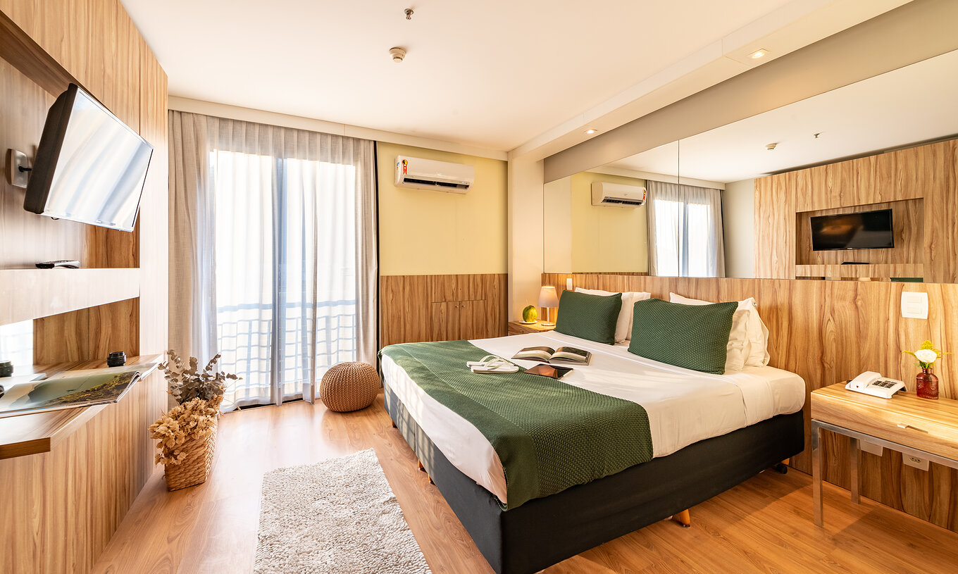 La Suite Vue Mer Latérale du Pestana Rio Atlântica a un lit double avec miroir au lit et une télévision en face