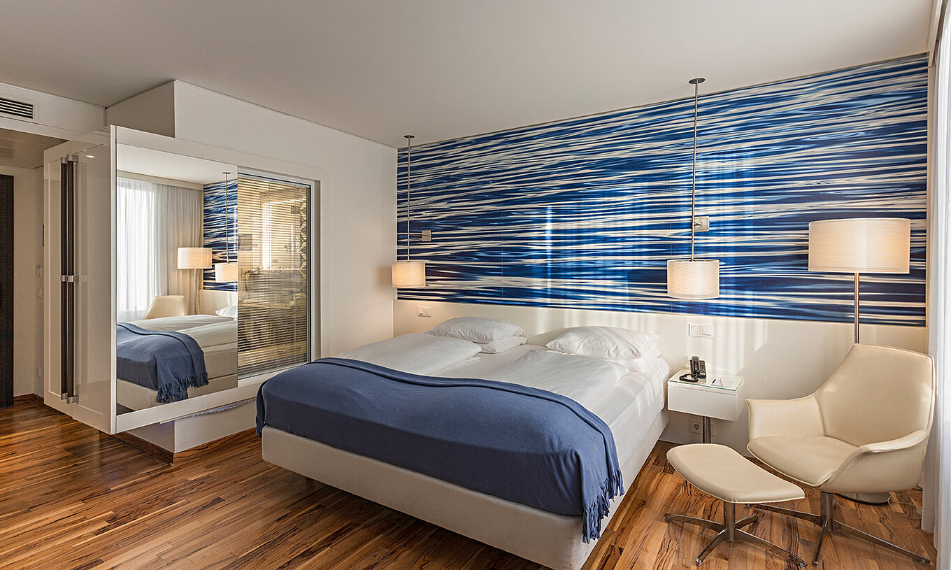 La Chambre Deluxe du Pestana Berlin Tiergarten a un Lit Double, une Table de Chevet avec Téléphone et un Canapé