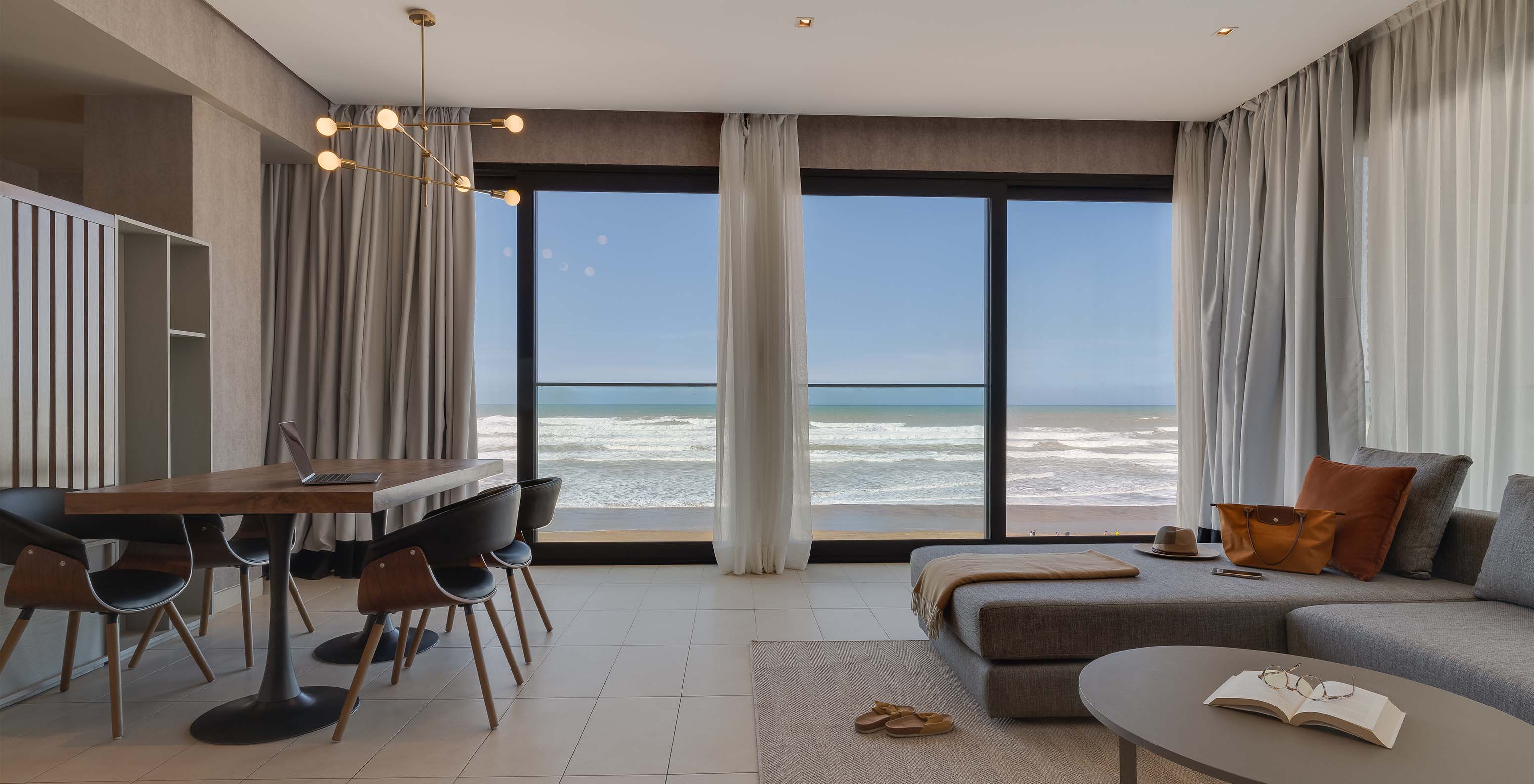 La Suite Familiale Corniche du Pestana Casablanca a un salon avec canapé et une vue spectaculaire sur la plage
