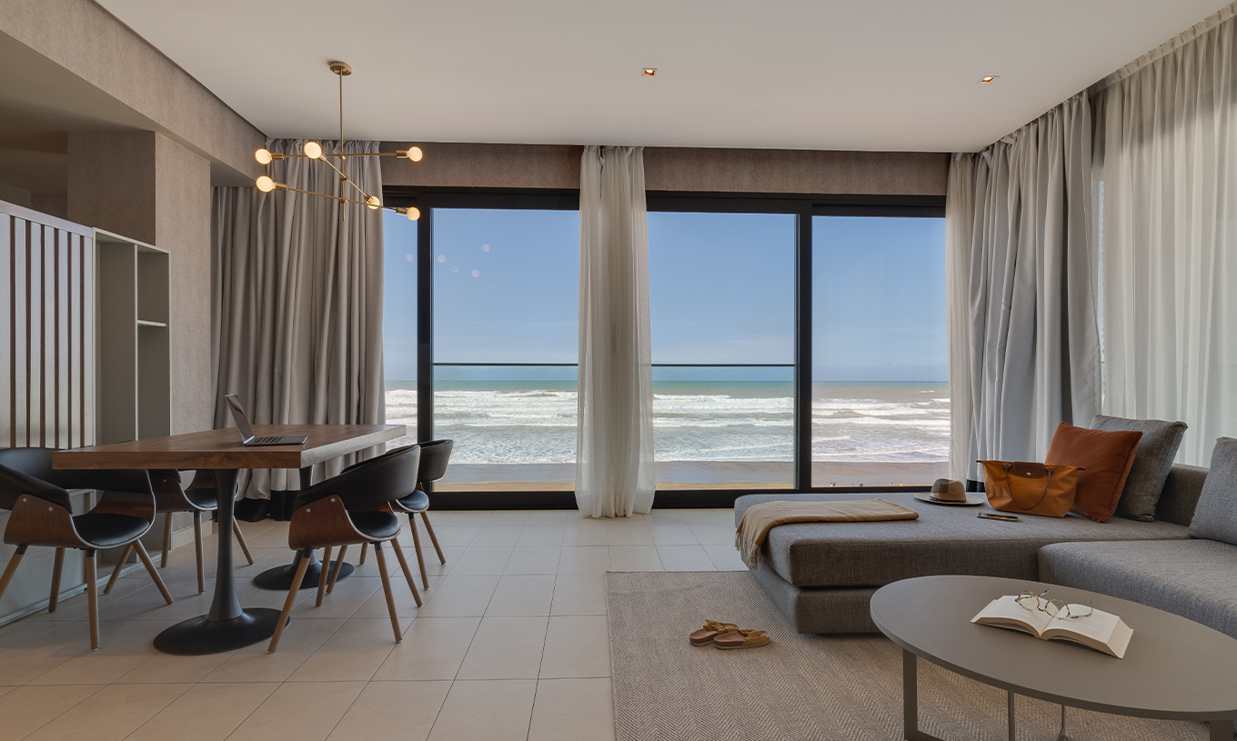 La Suite Familiale Corniche du Pestana Casablanca a un salon avec canapé et une vue spectaculaire sur la plage