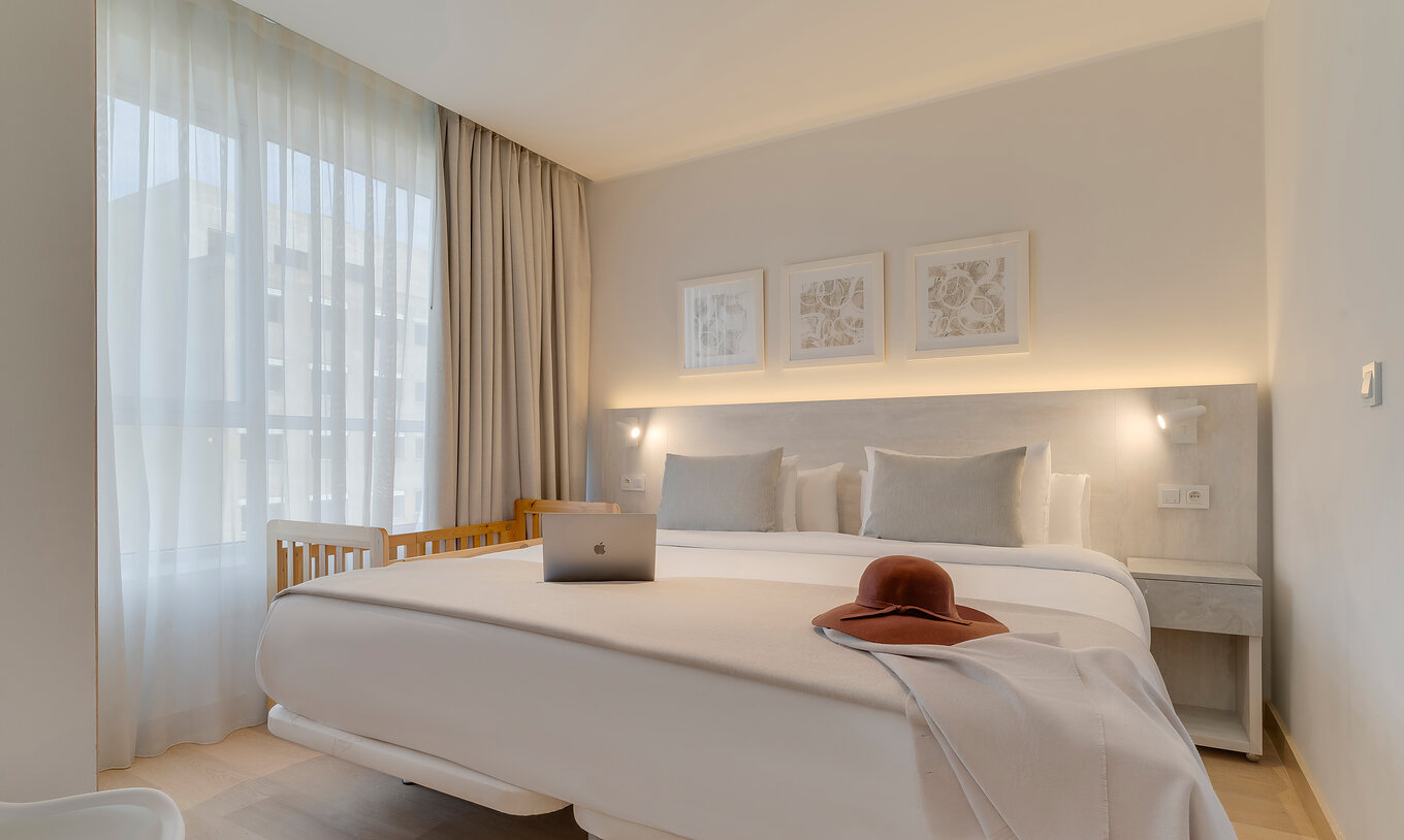 La suite du Pestana Tanger City Center a un lit double avec tête de lit en pierre, un berceau à côté et une fenêtre