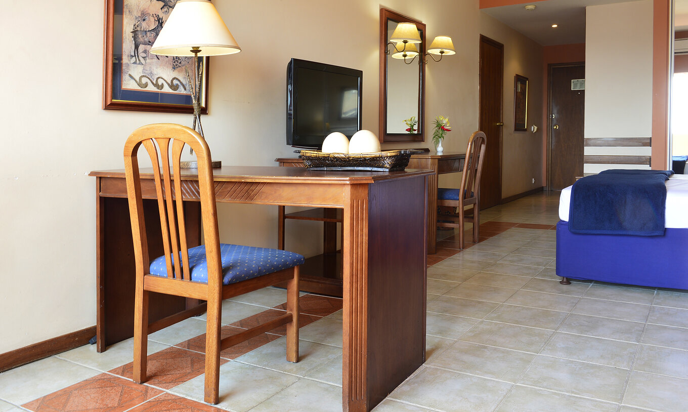 La Suite Exécutive Familiale du Pestana Rovuma a un bureau et une chaise en bois, avec une lampe et un tableau