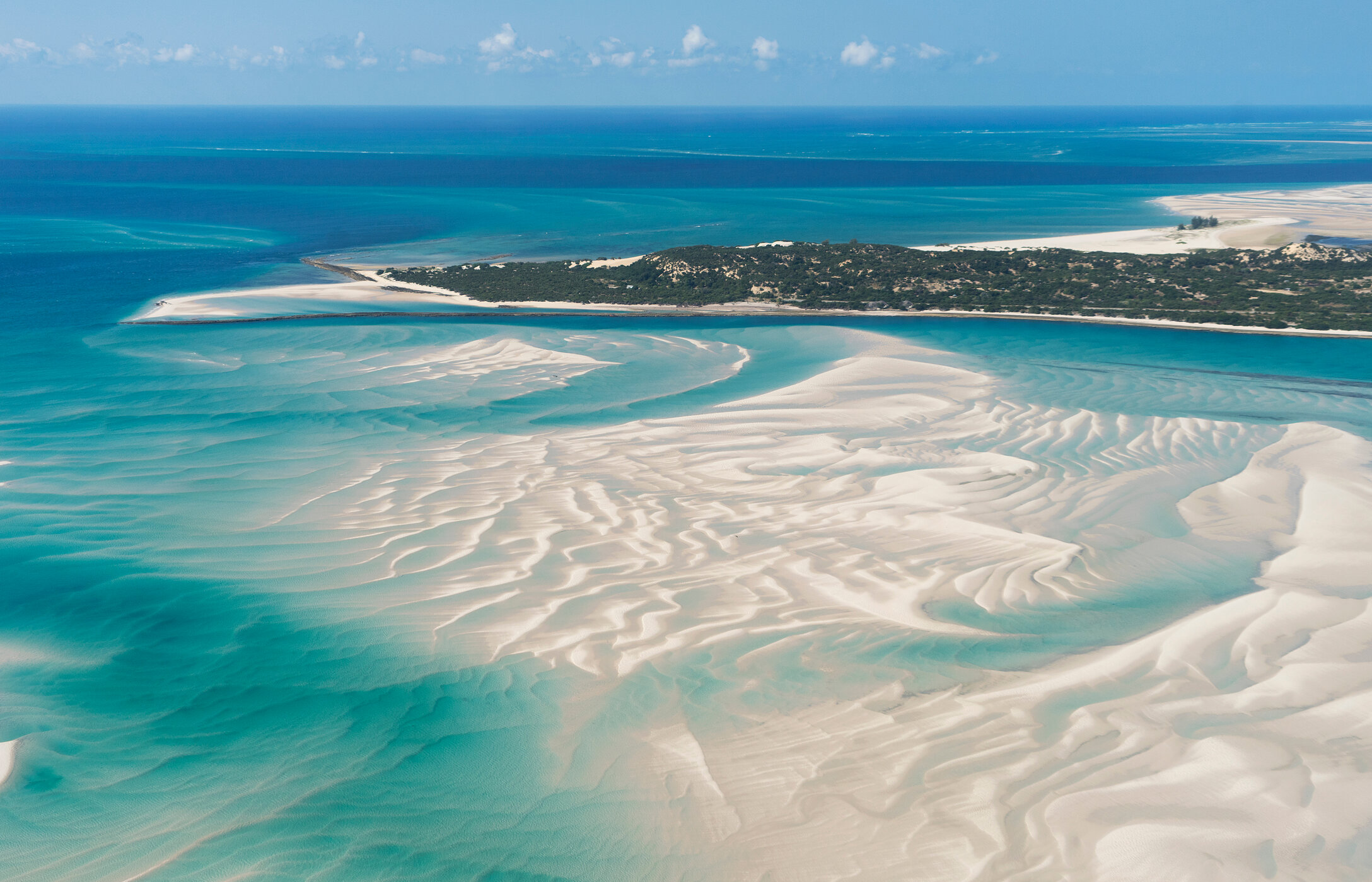 Vue aérienne de l'île de Vilankulo, Mozambique, avec des eaux cristallines, des bancs de sable et de la végétation.