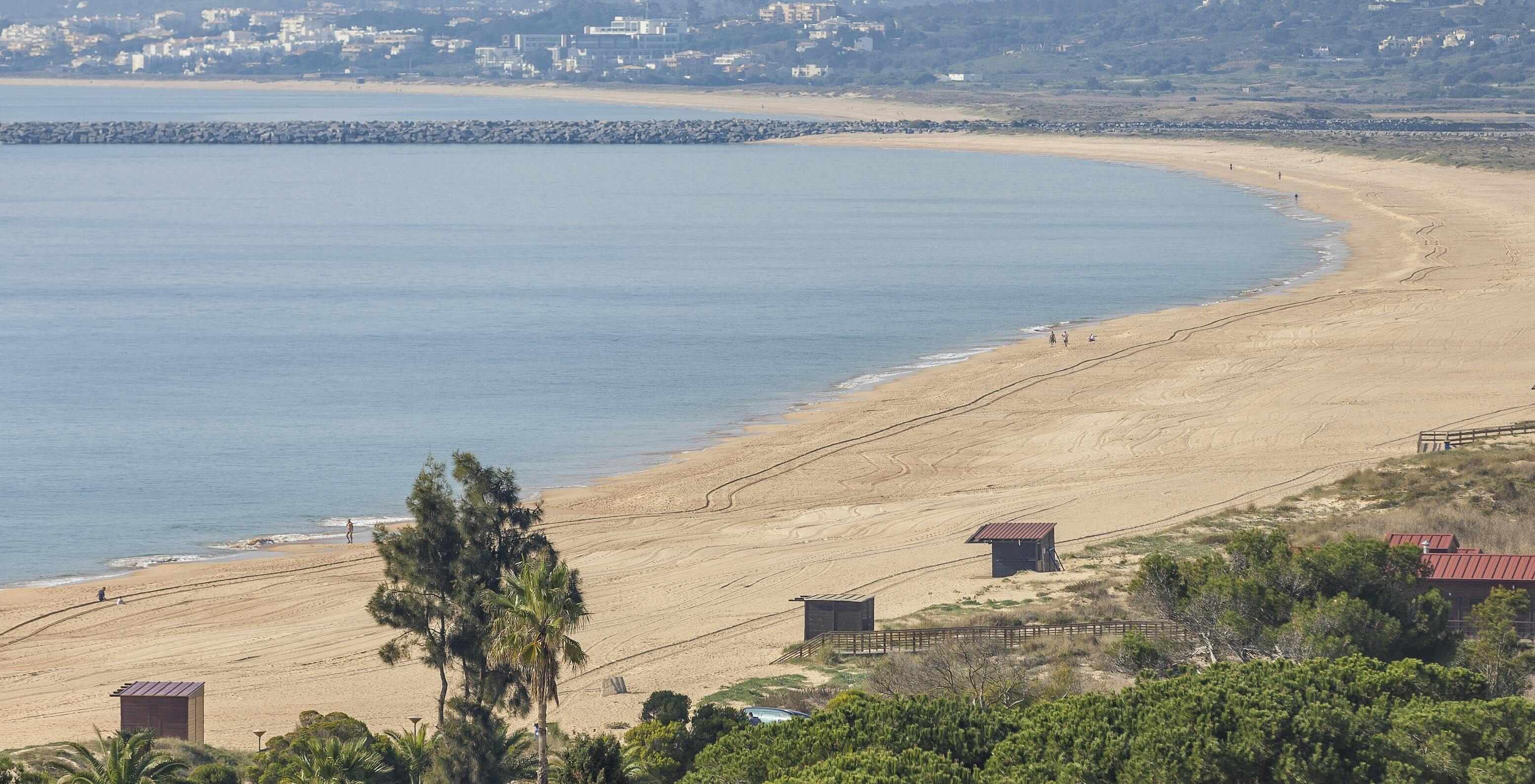 La plage d'Alvor, en Algarve, a du sable doré, une eau cristalline, une passerelle et des dunes
