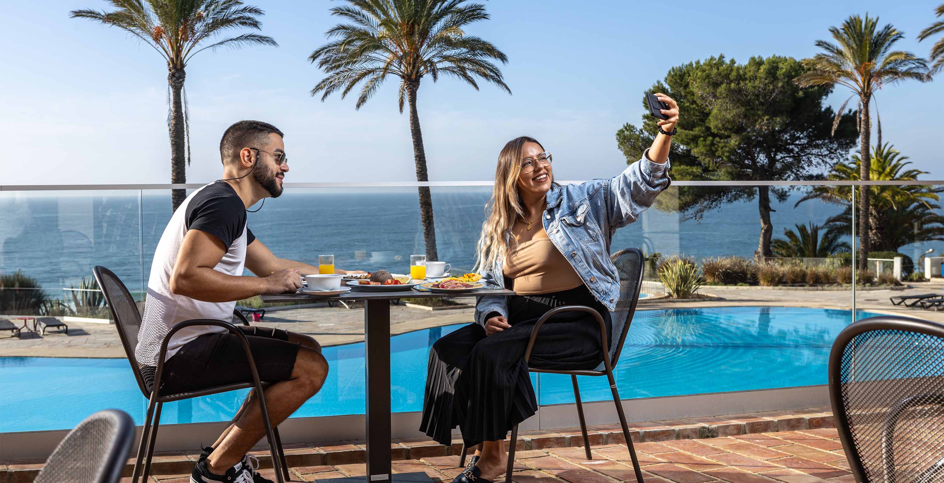 Couple prenant un selfie pendant le petit-déjeuner sur la terrasse du restaurant du Pestana Alvor Praia, avec vue sur la mer
