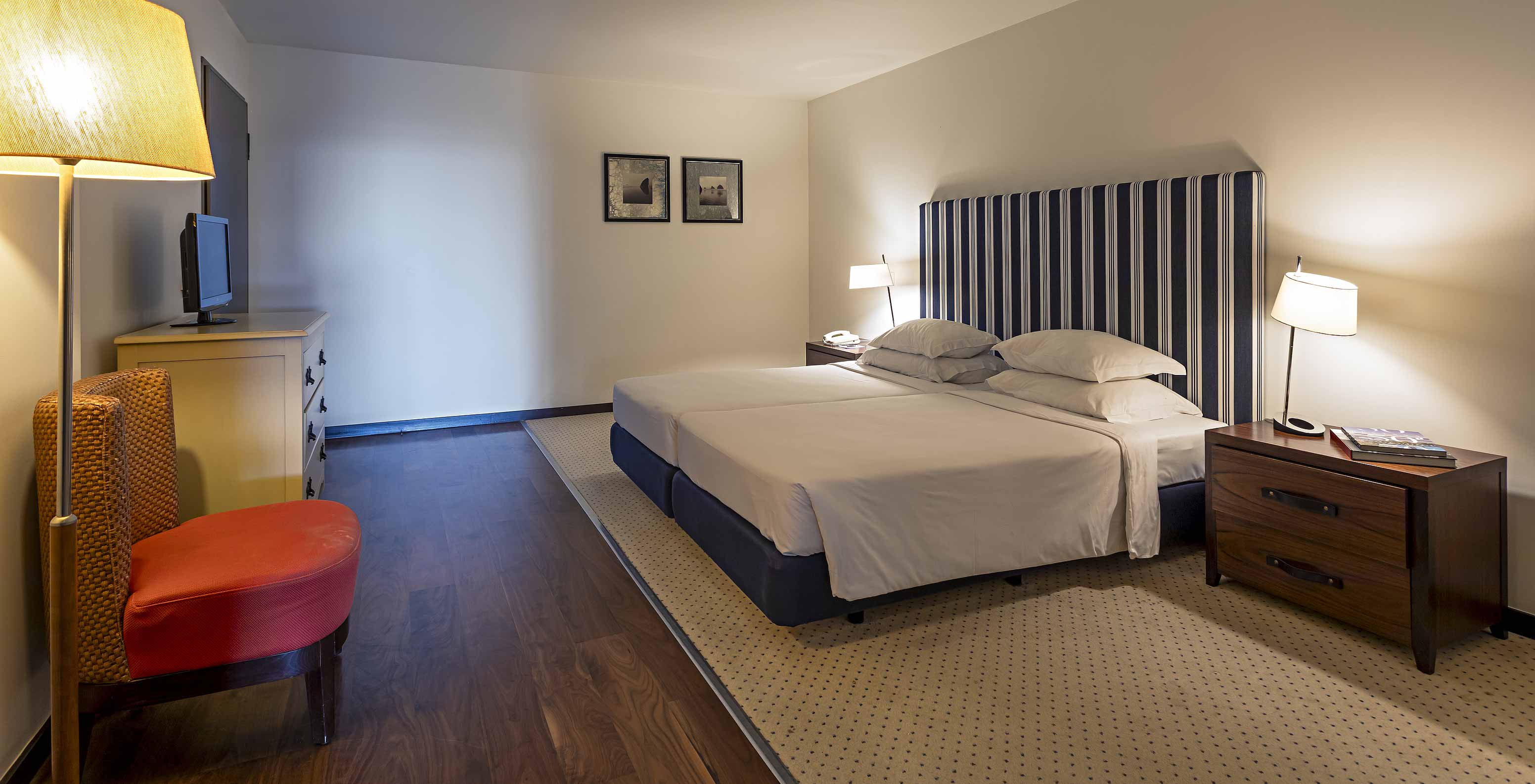 La suite Cliff T2 du Pestana Alvor Praia a une grande chambre avec lit double, deux tableaux et une commode avec TV