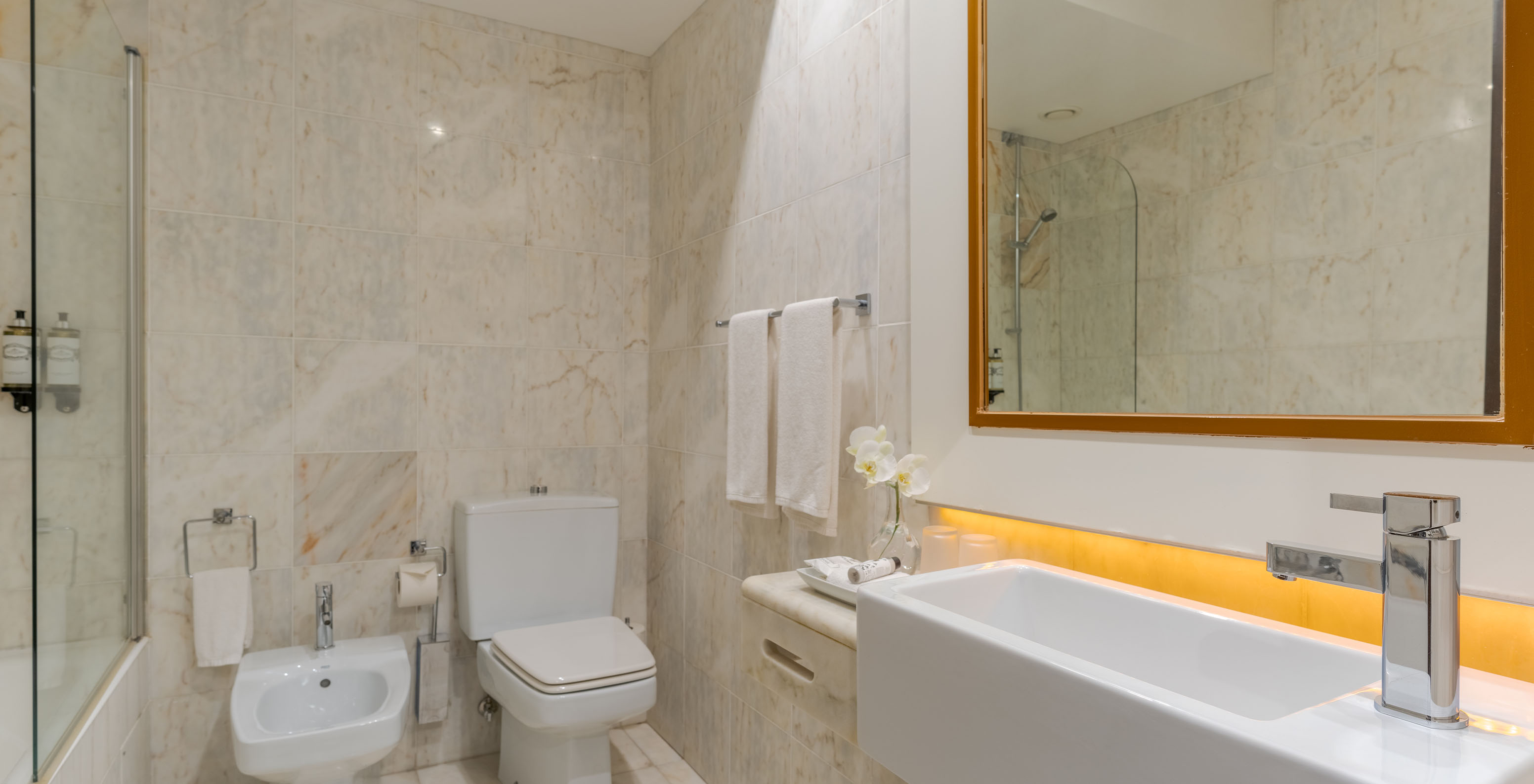 Le Deluxe Vue Jardin du Pestana Alvor Praia a une salle de bain en marbre avec lavabo, miroir, WC, bidet et baignoire