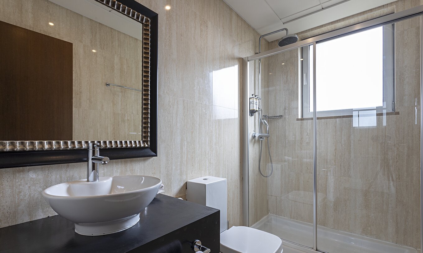 La suite Cliff T2 du Pestana Alvor Praia a une salle de bain moderne avec fenêtre, douche, lavabo et miroir
