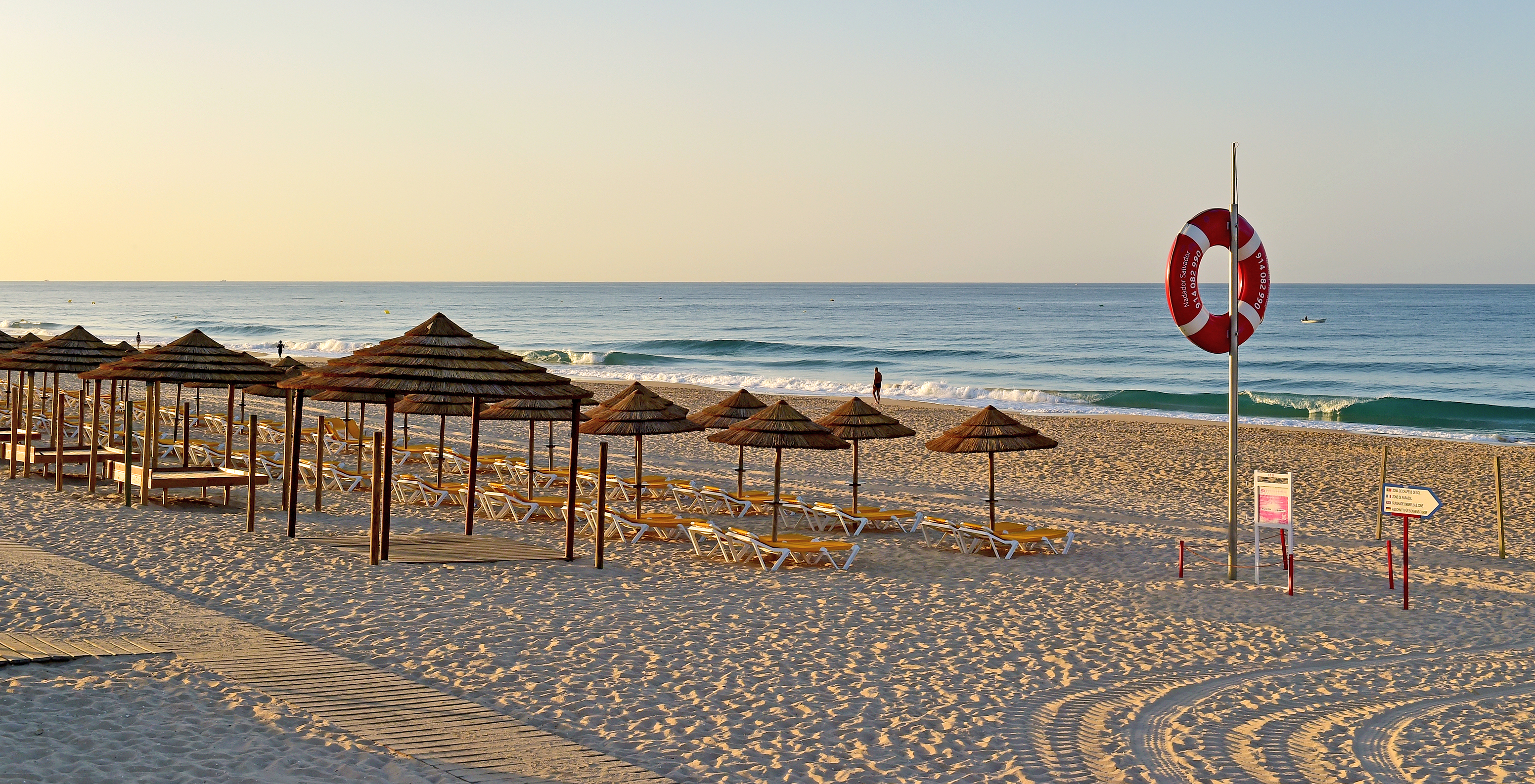 Chaises longues sur la plage d'Alvor, avec du sable clair et de petites vagues, un cadre de paix et de tranquillité