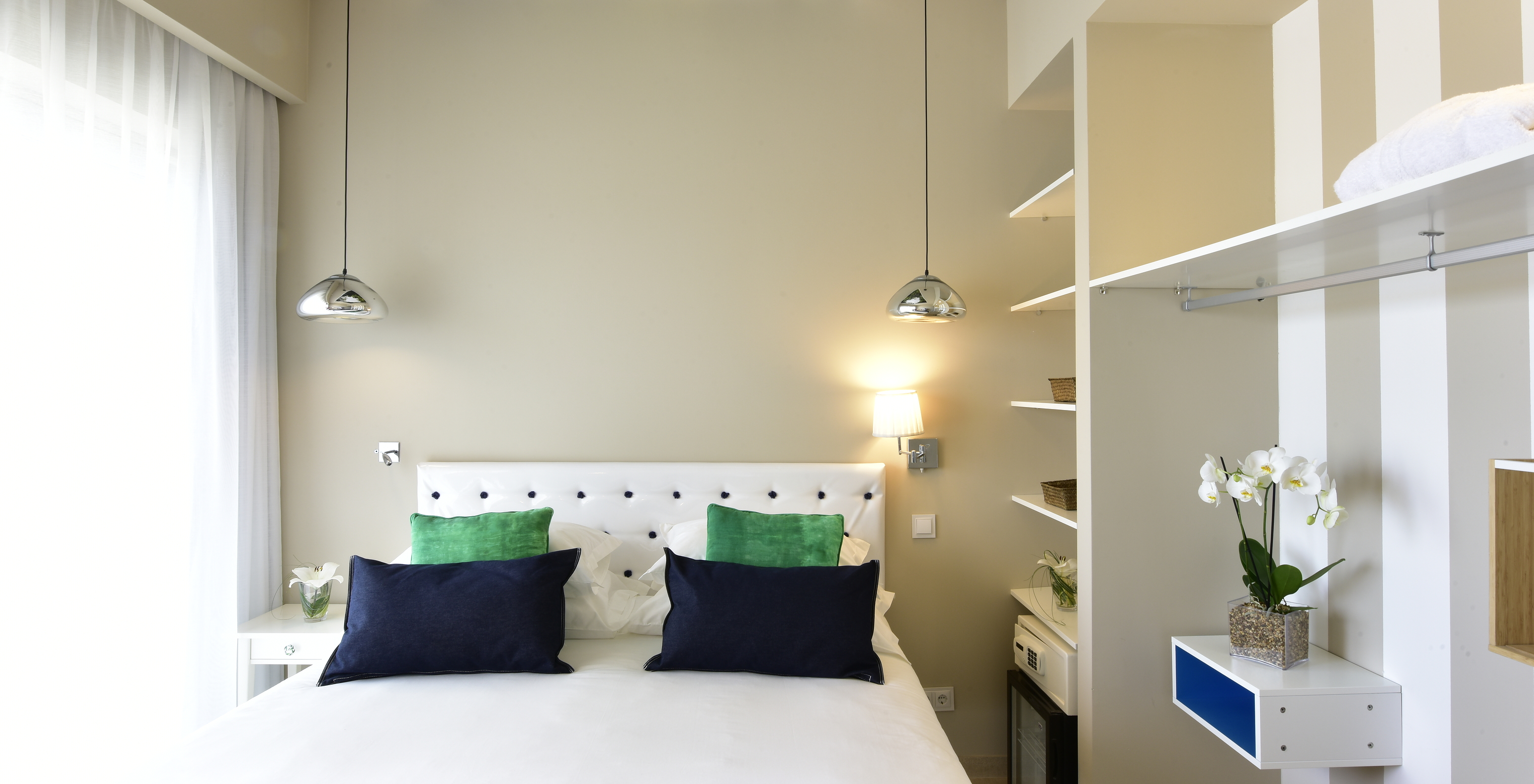 La Suite du Pestana Alvor South Beach a un lit double avec fenêtre d'un côté et un placard ouvert avec minibar