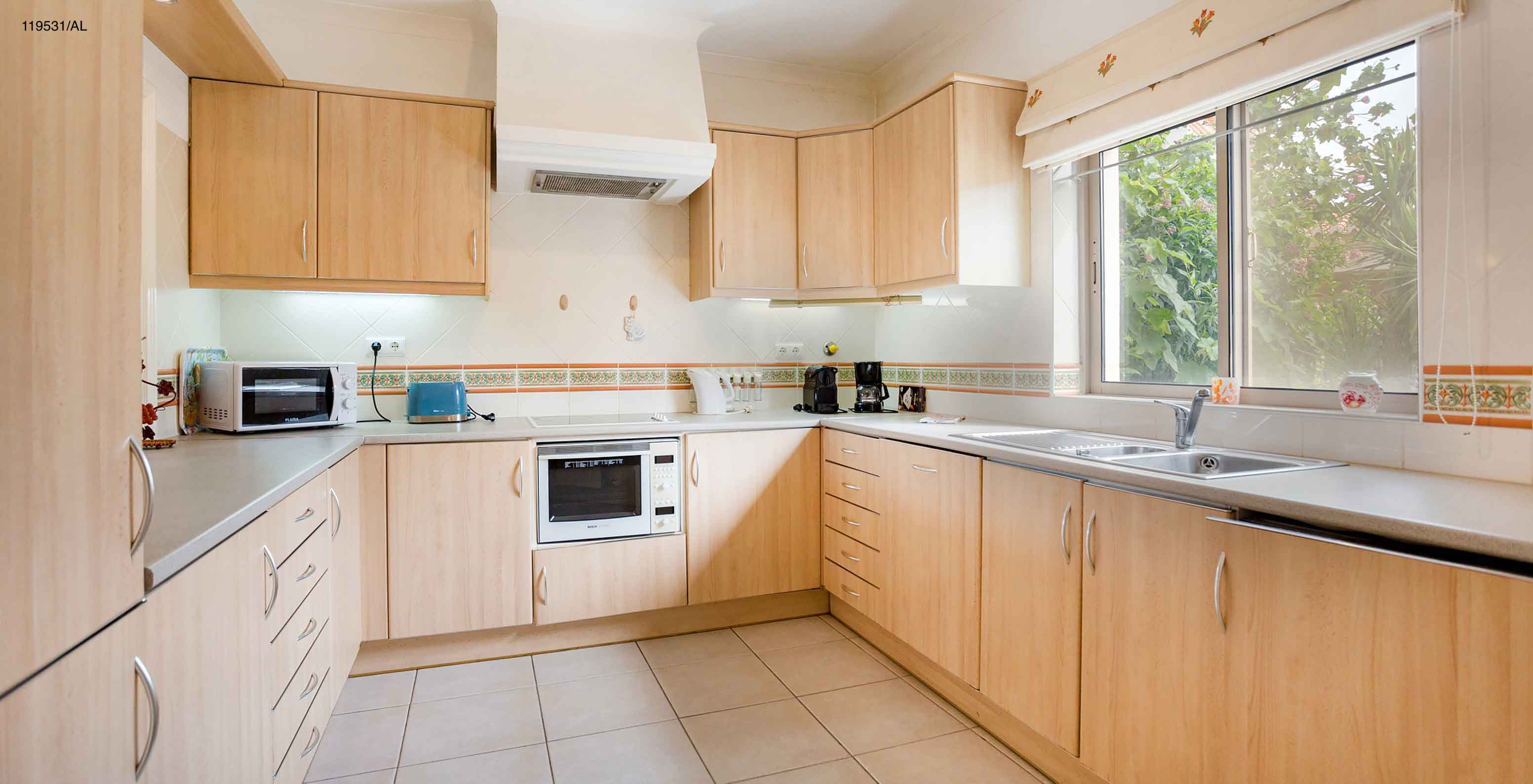 L'appartement Pestana Carvoeiro Golf T1 Standard dispose d'une cuisine avec des armoires en bois et des appareils