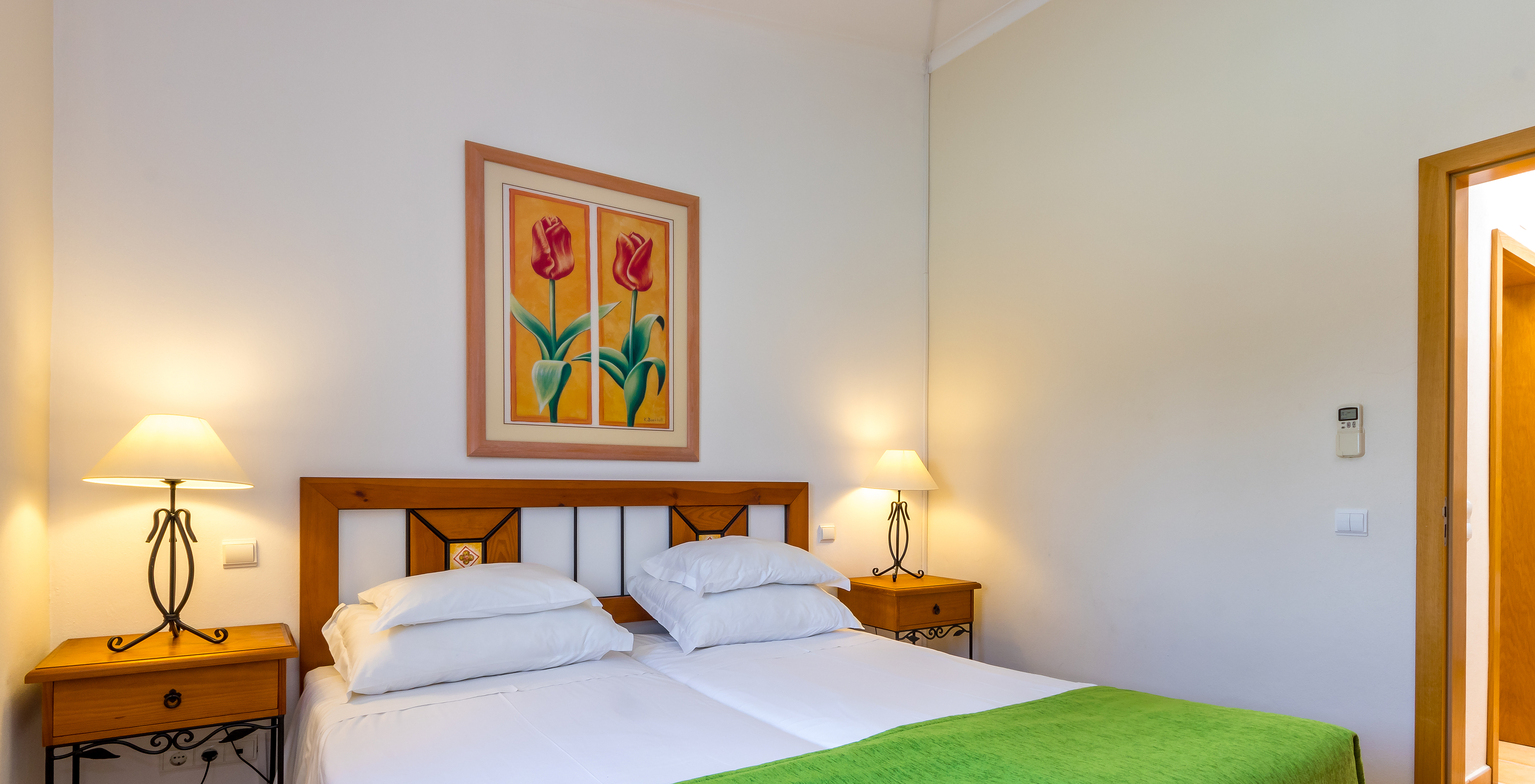 L'Appartement T1 - Terra du Pestana Palm Gardens a deux lits jumeaux, avec couvre-lit vert et un tableau avec deux fleurs