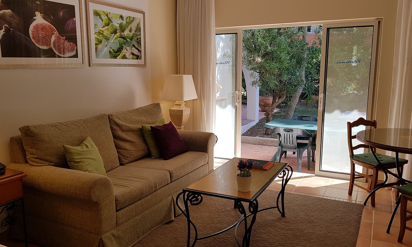 L'Étude du Pestana Palm Gardens a un salon avec canapé et une fenêtre donnant accès au jardin