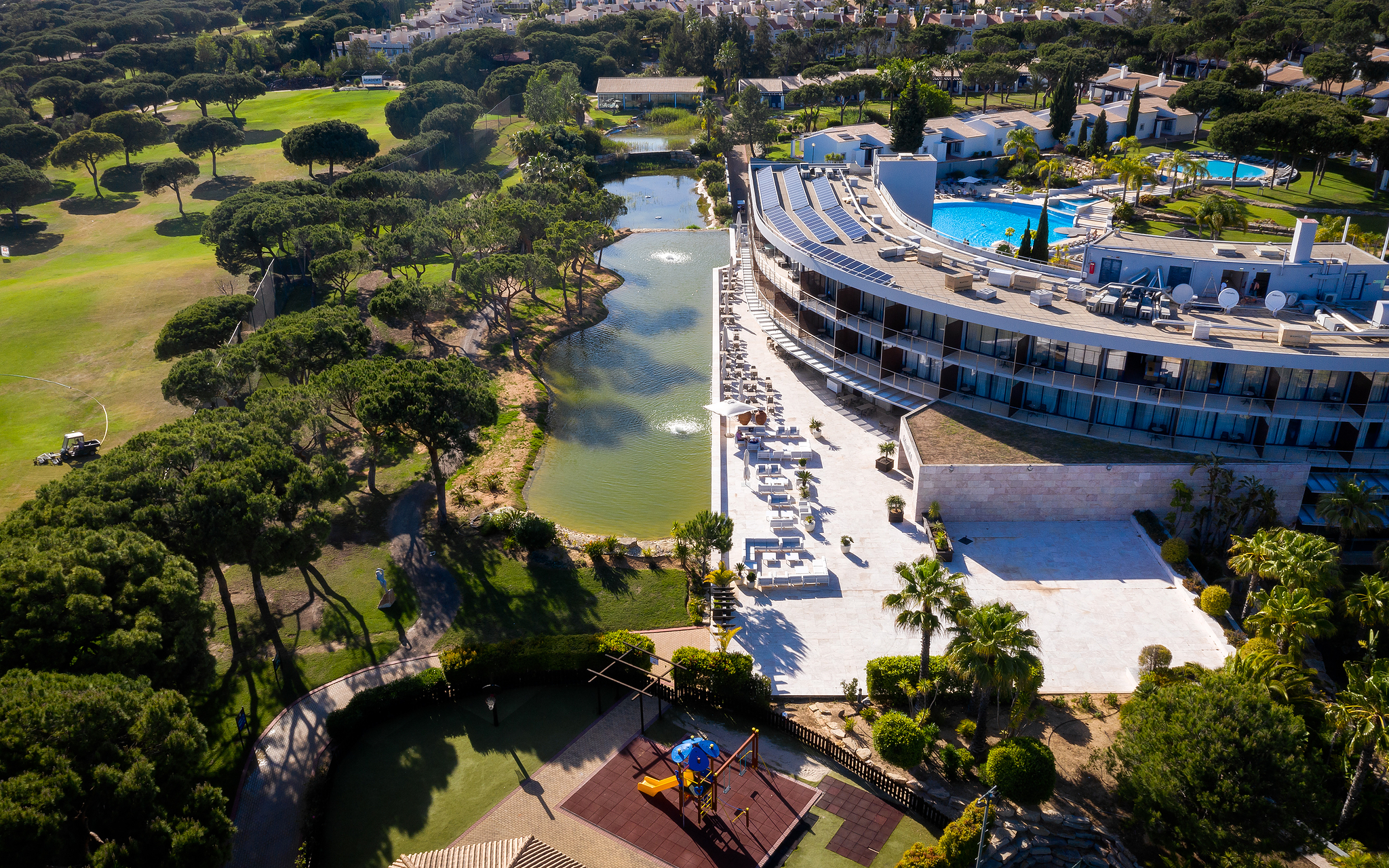 Vue du Pestana Vila Sol - Vilamoura, un hôtel 5 étoiles à Vilamoura avec piscine, entouré d'un lac et de verdure