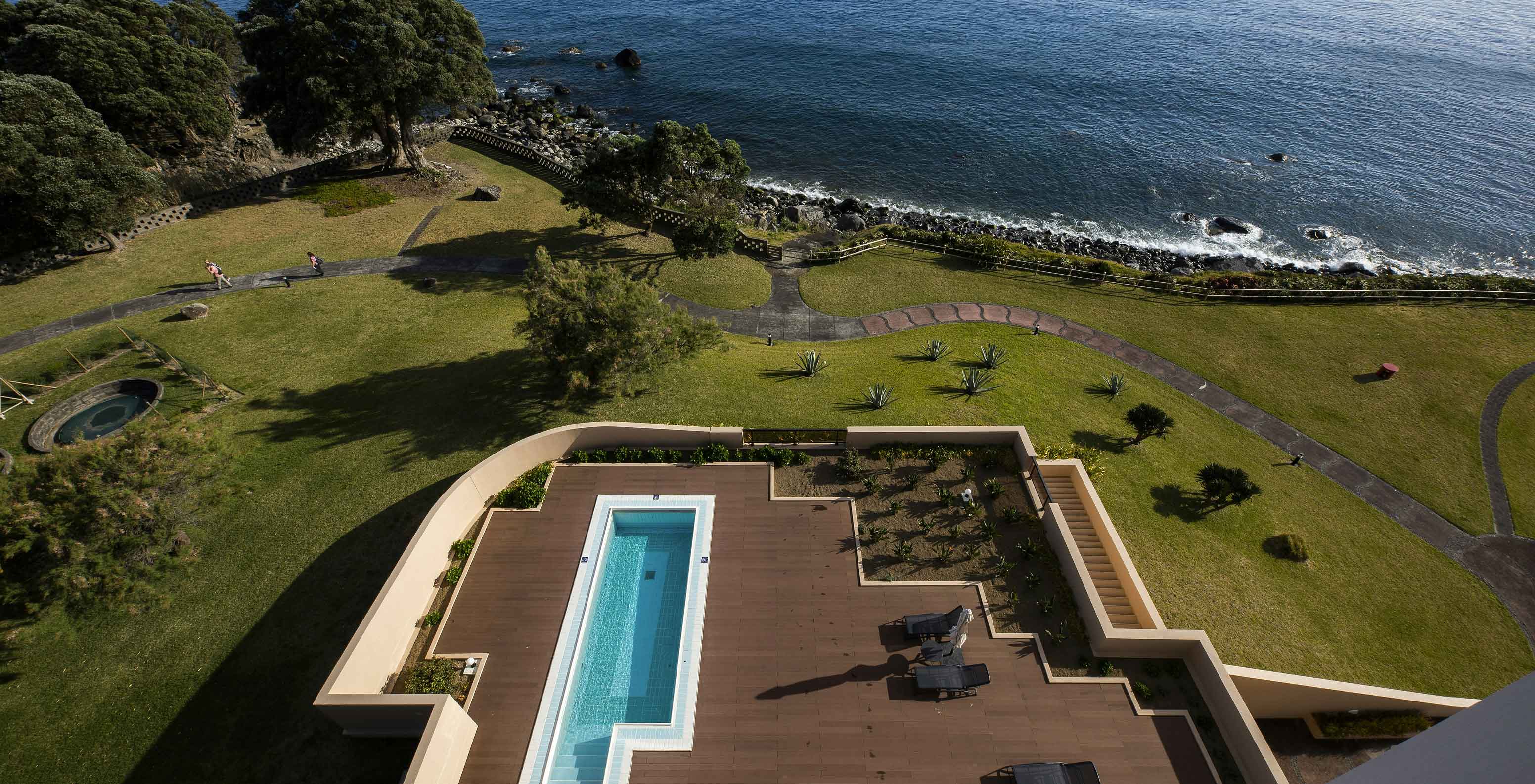 Piscine du Pestana Bahia Praia sur terrasse en bois avec vue sur la mer et zone verte autour