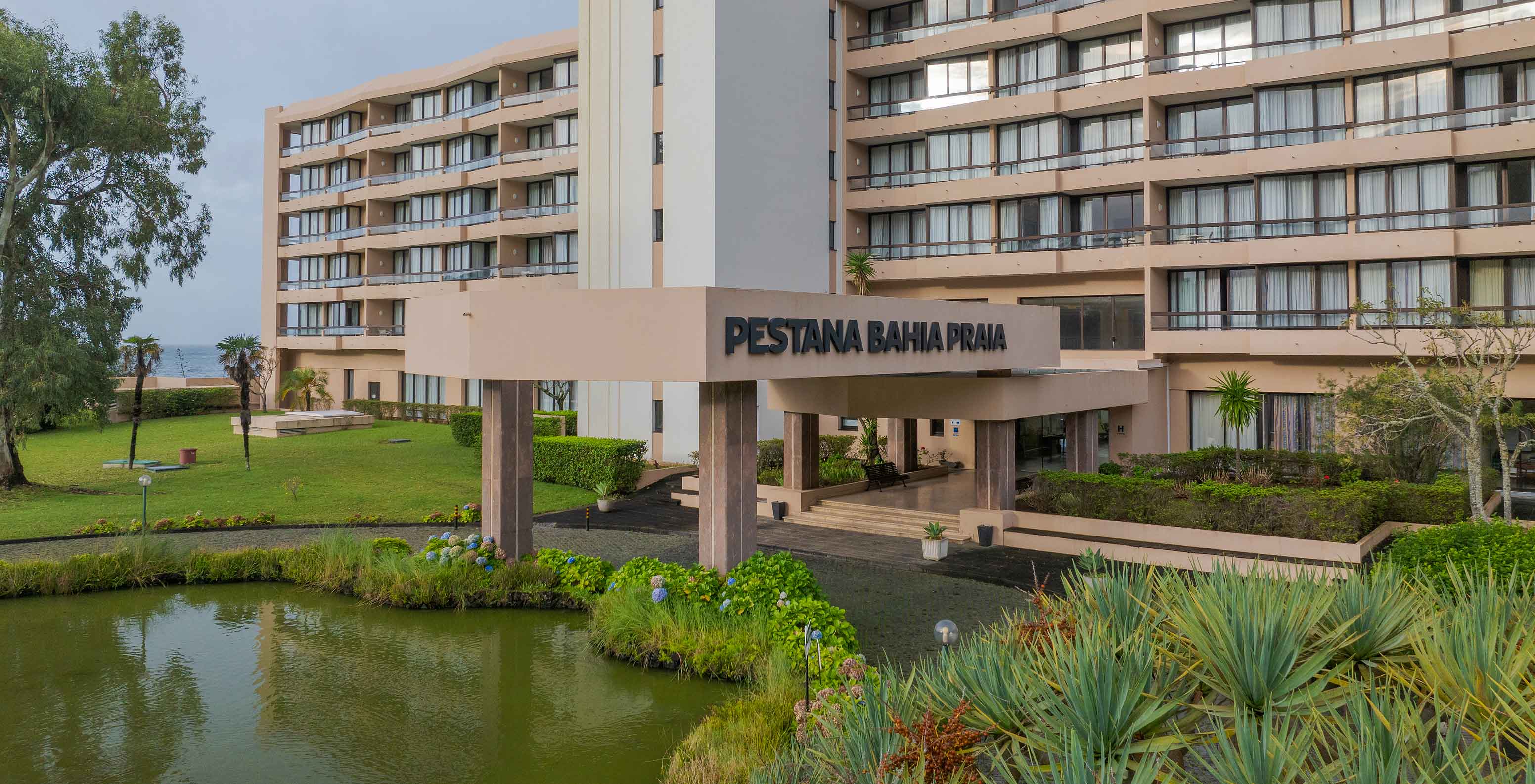 Entrée principale du Pestana Bahia Praia avec étang, végétation tropicale et façade moderne en arrière-plan