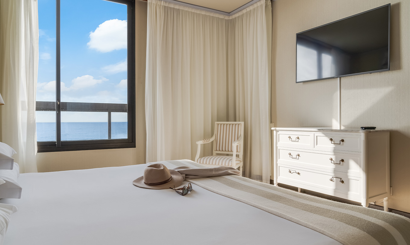 La Suite du Pestana Bahia Praia a un lit double avec une fenêtre à gauche et une télévision au pied du lit