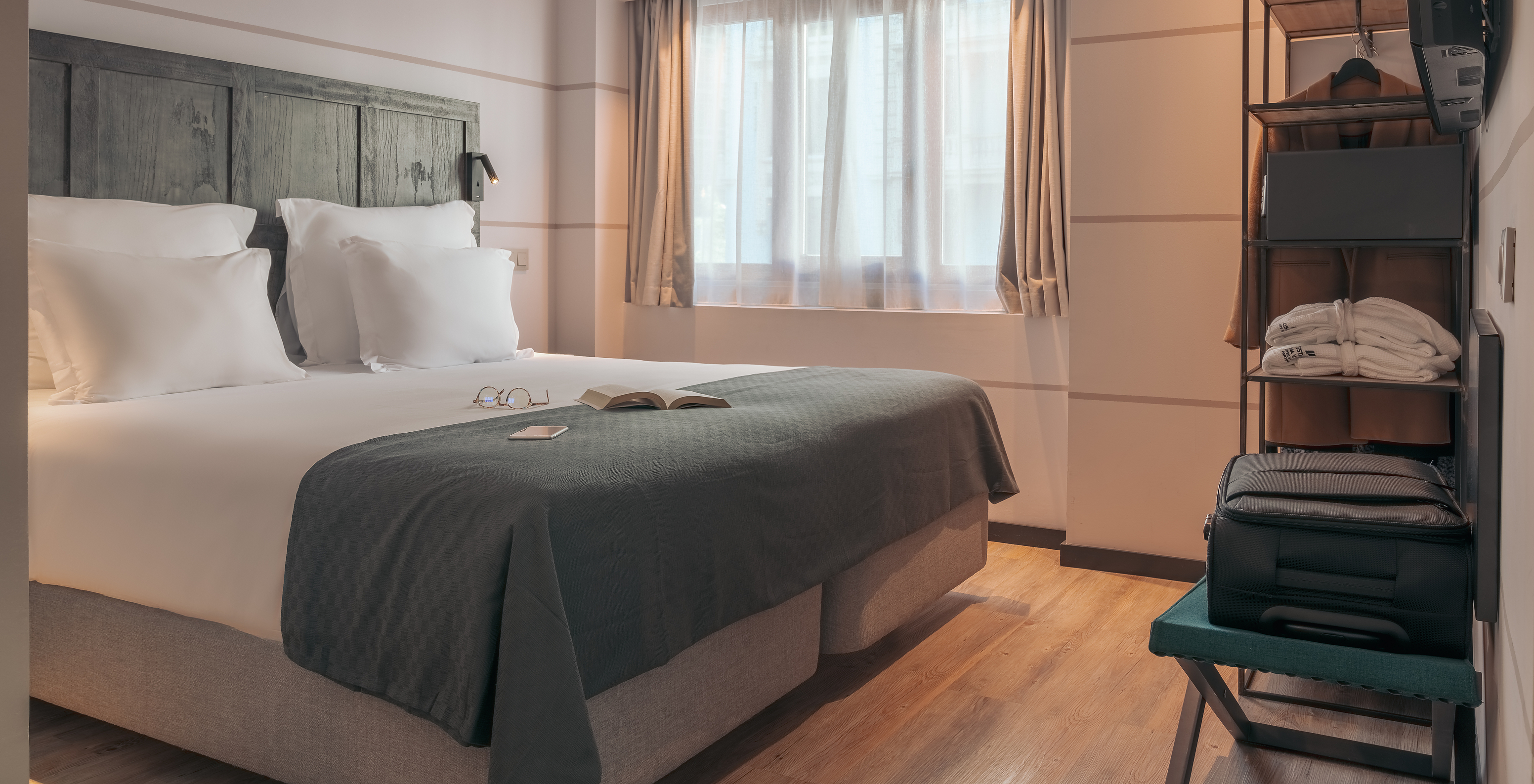 Le Double Deluxe Studio du Pestana Lisboa Vintage a un lit double avec une couverture grise et une armoire avec un manteau